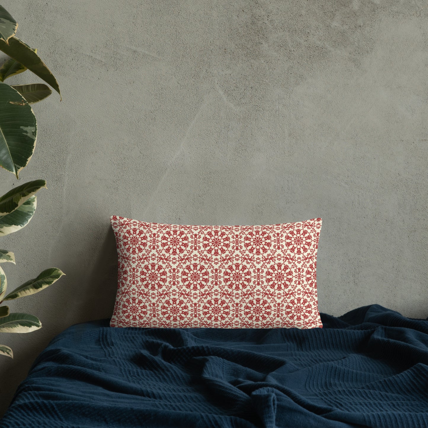 20″×12″ throw pillow with the ‘Decagon’ terracotta and beige geometric pattern on a bed with a dark navy blanket.