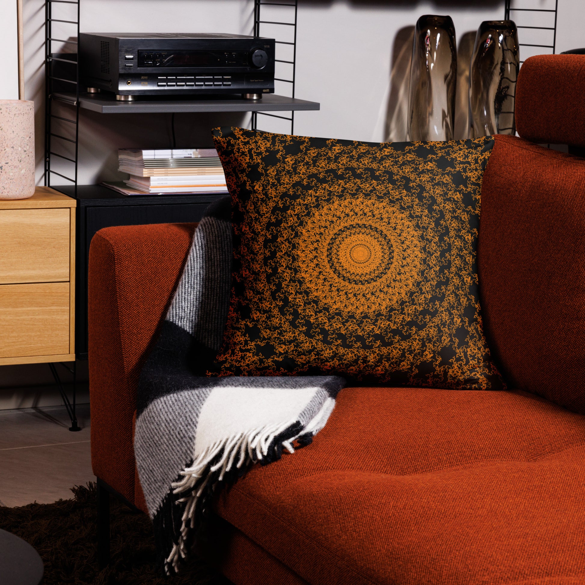 22″×22″ throw pillow with the 'The Sun' orange and black geometric design on a couch.