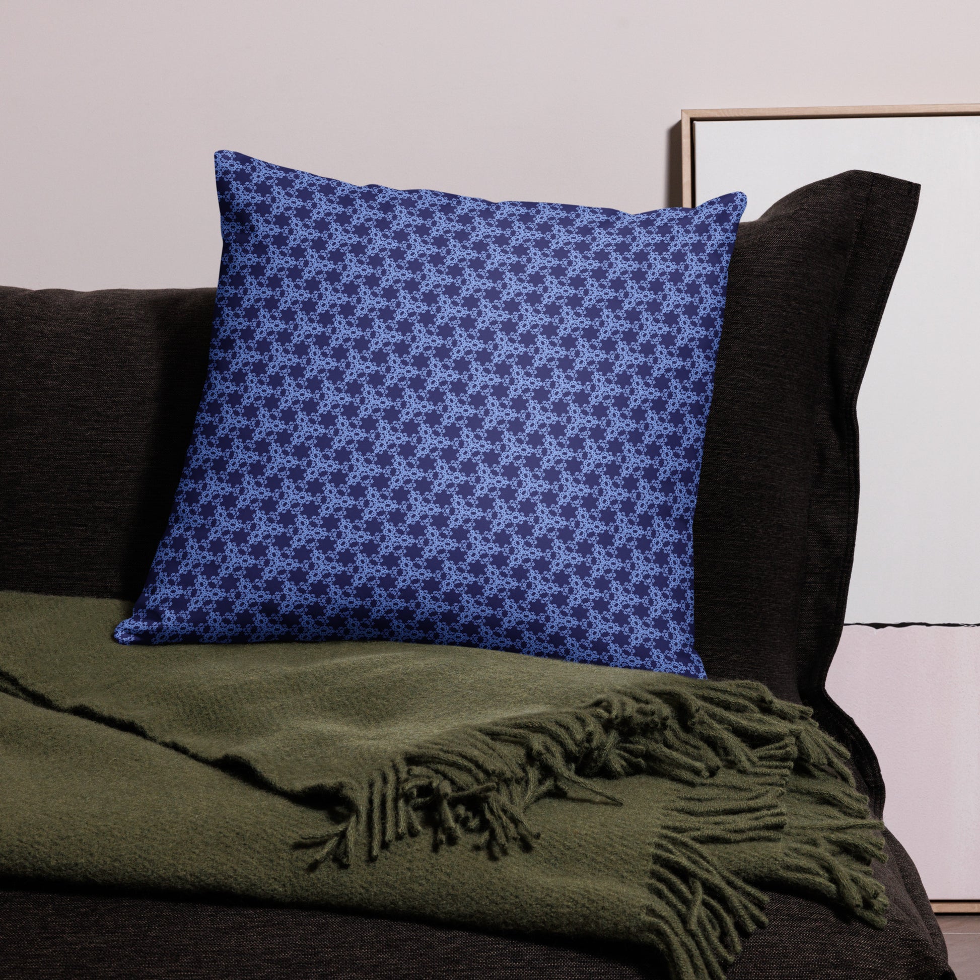 22″×22″ throw pillow with the 'Trigon' navy and blue geometric pattern on a couch.
