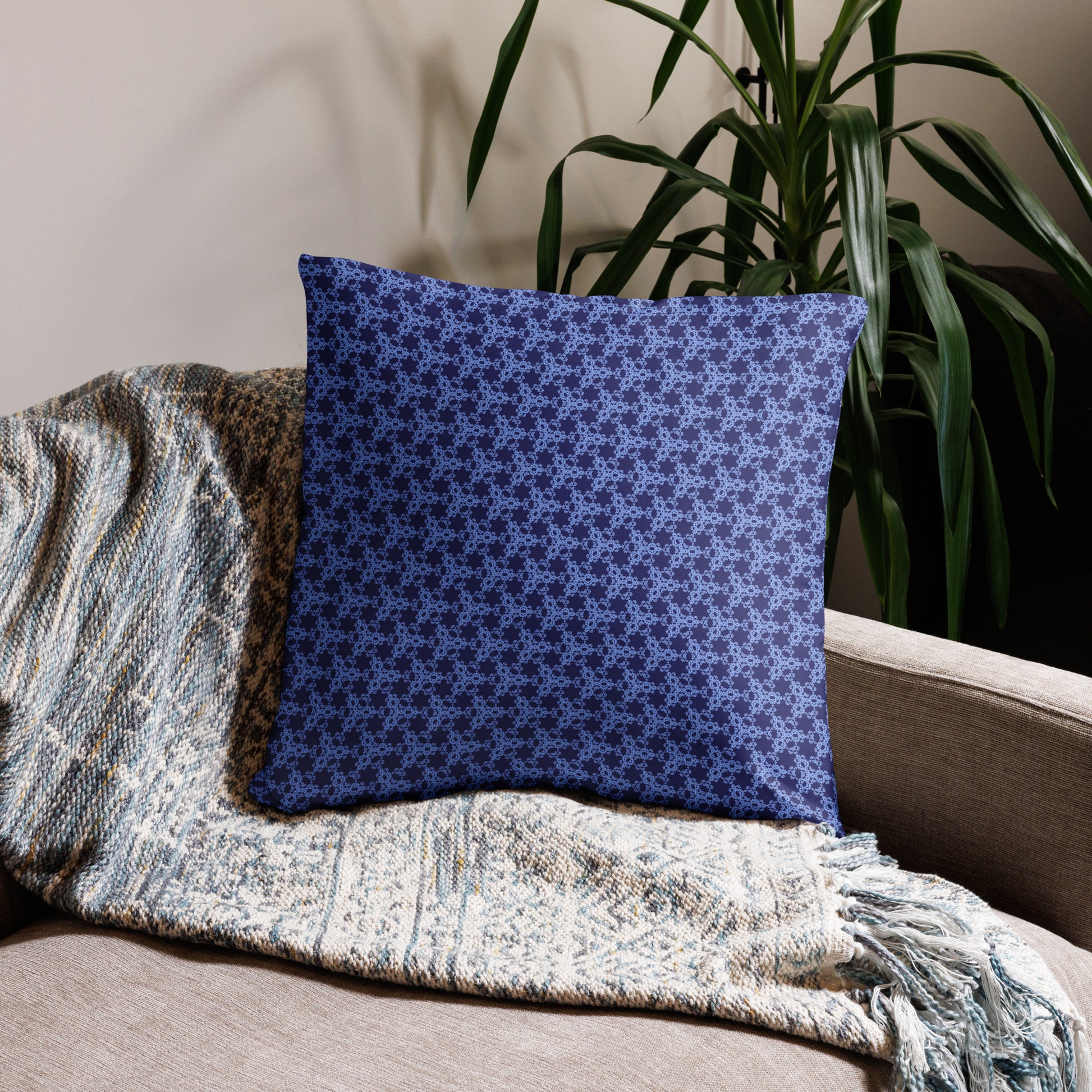 22″×22″ throw pillow with the 'Trigon' navy and blue geometric pattern on a couch.
