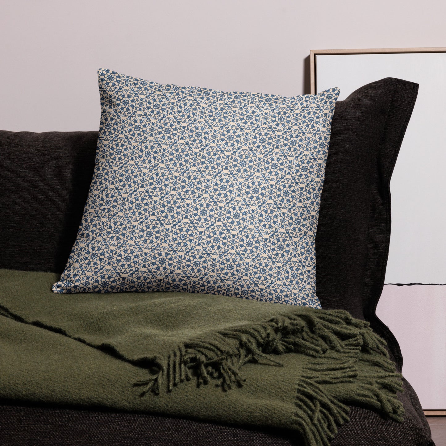 22″×22″ throw pillow with the ‘Octagon’ navy and beige geometric pattern on a dark sofa with throw blanket.