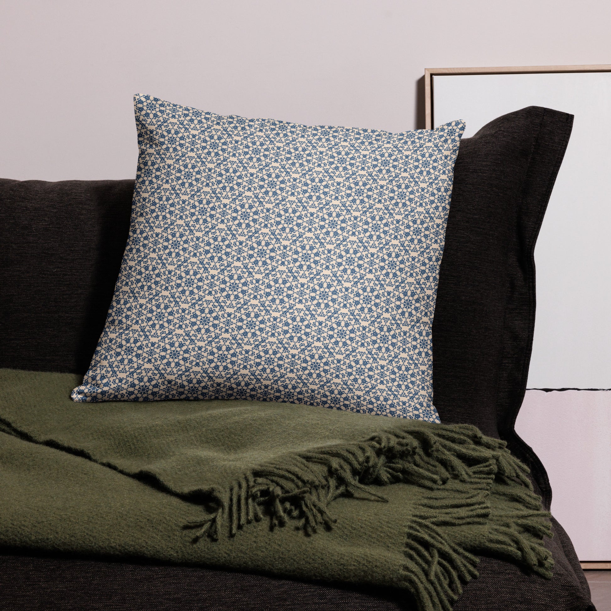 22″×22″ throw pillow with the ‘Octagon’ navy and beige geometric pattern on a dark sofa with throw blanket.