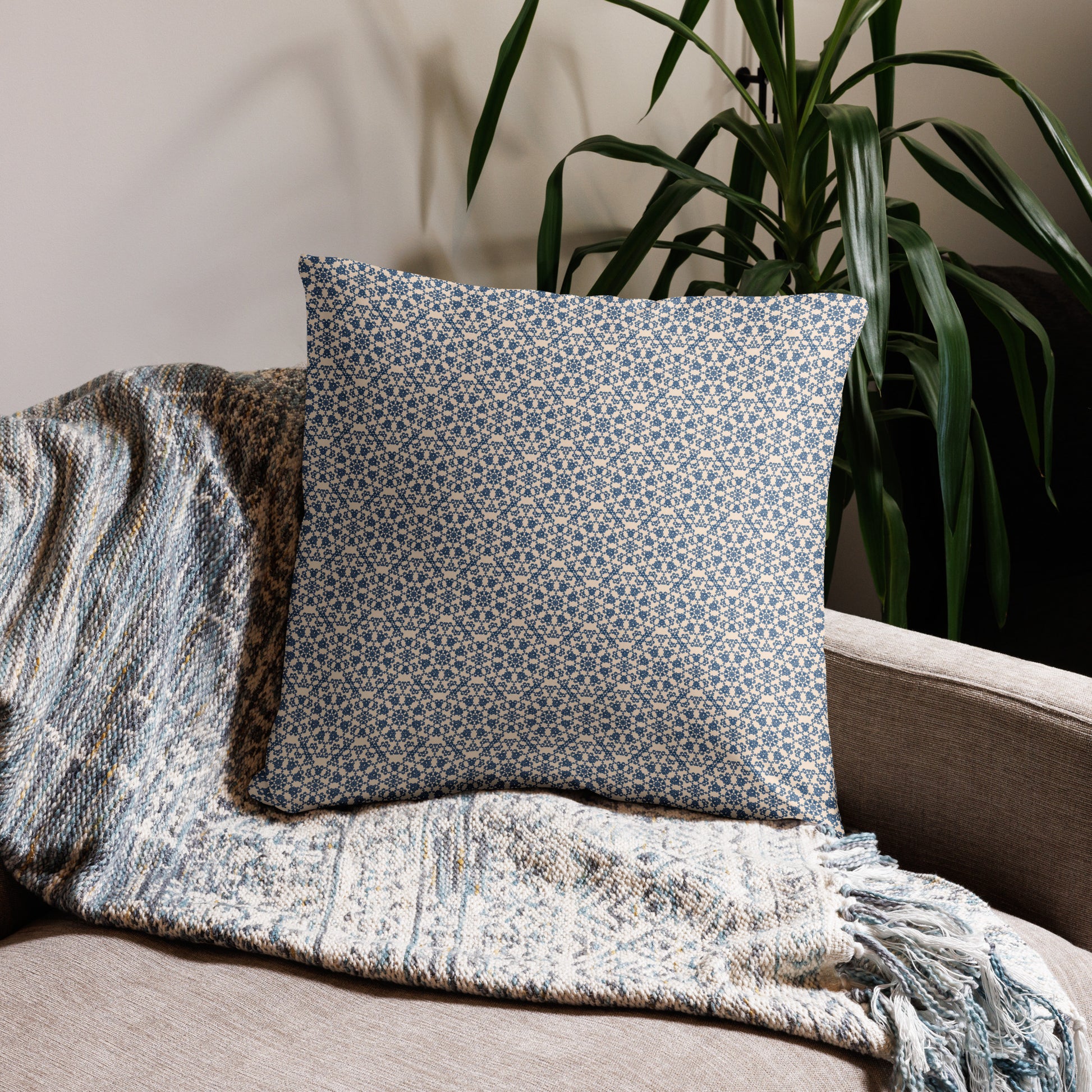 22″×22″ throw pillow with the ‘Octagon’ navy and beige geometric pattern on a sofa with fringed blanket.