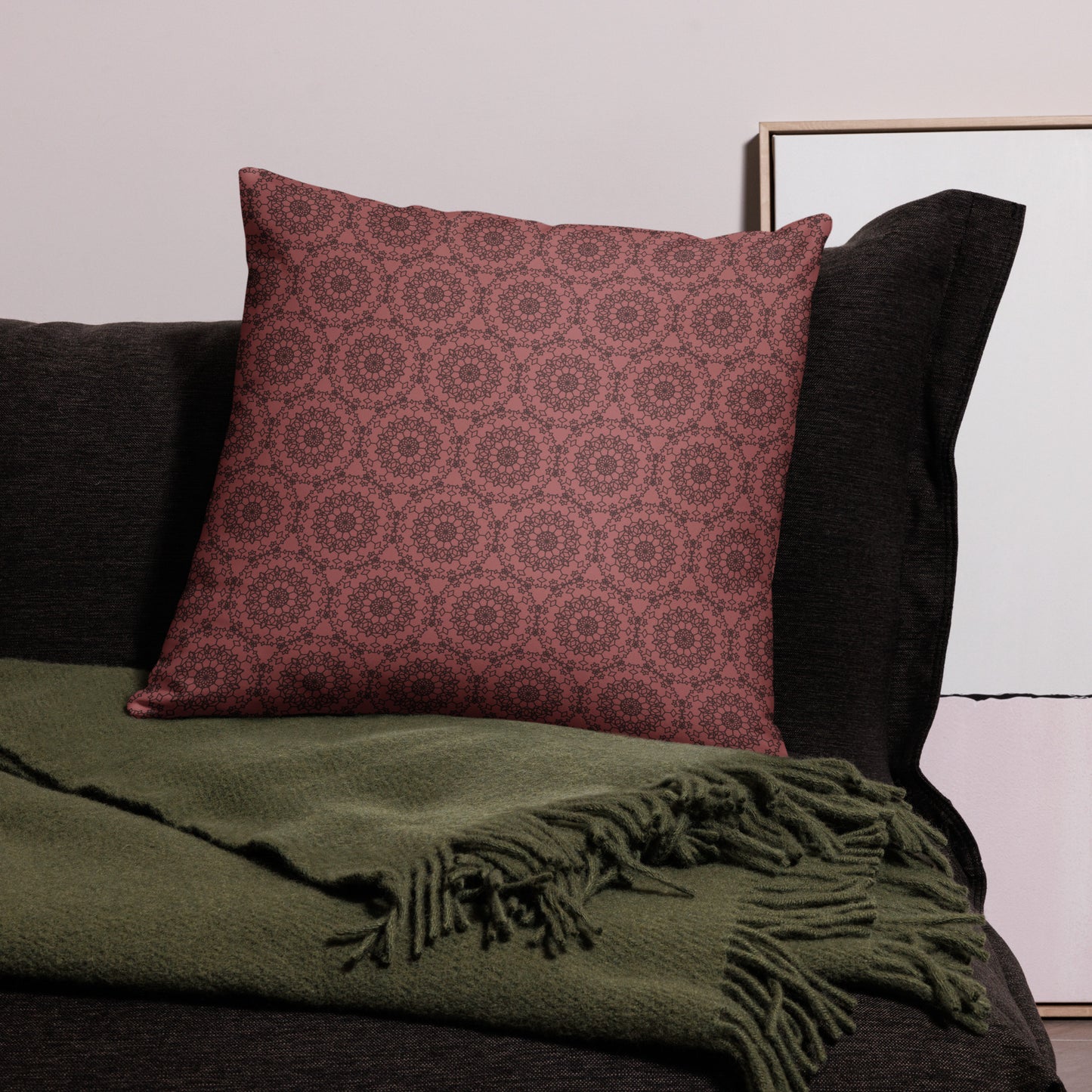 22″×22″ throw pillow with the 'Dodecagon' rose geometric pattern on dark sofa with green fringed throw.
