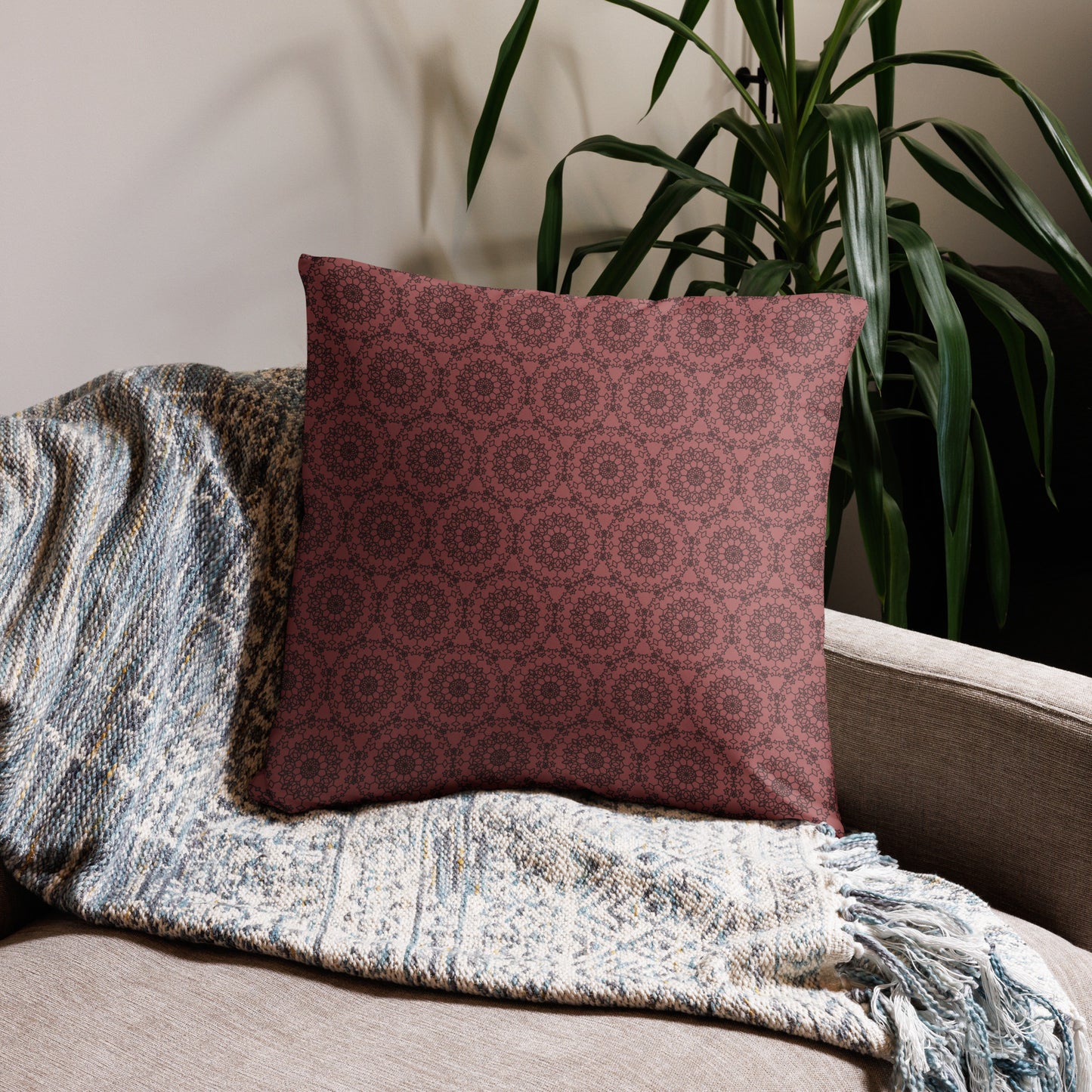 22″×22″ throw pillow with the 'Dodecagon' rose geometric pattern on beige sofa with woven throw blanket.