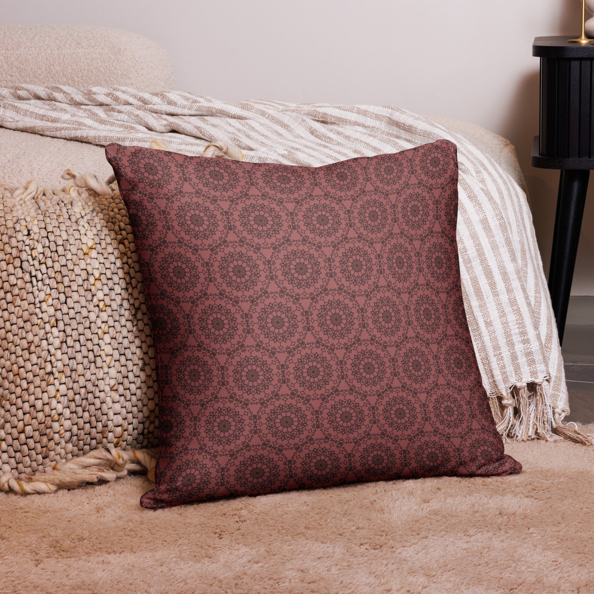 22″×22″ throw pillow with the 'Dodecagon' rose geometric pattern on carpet beside bed with striped throw.