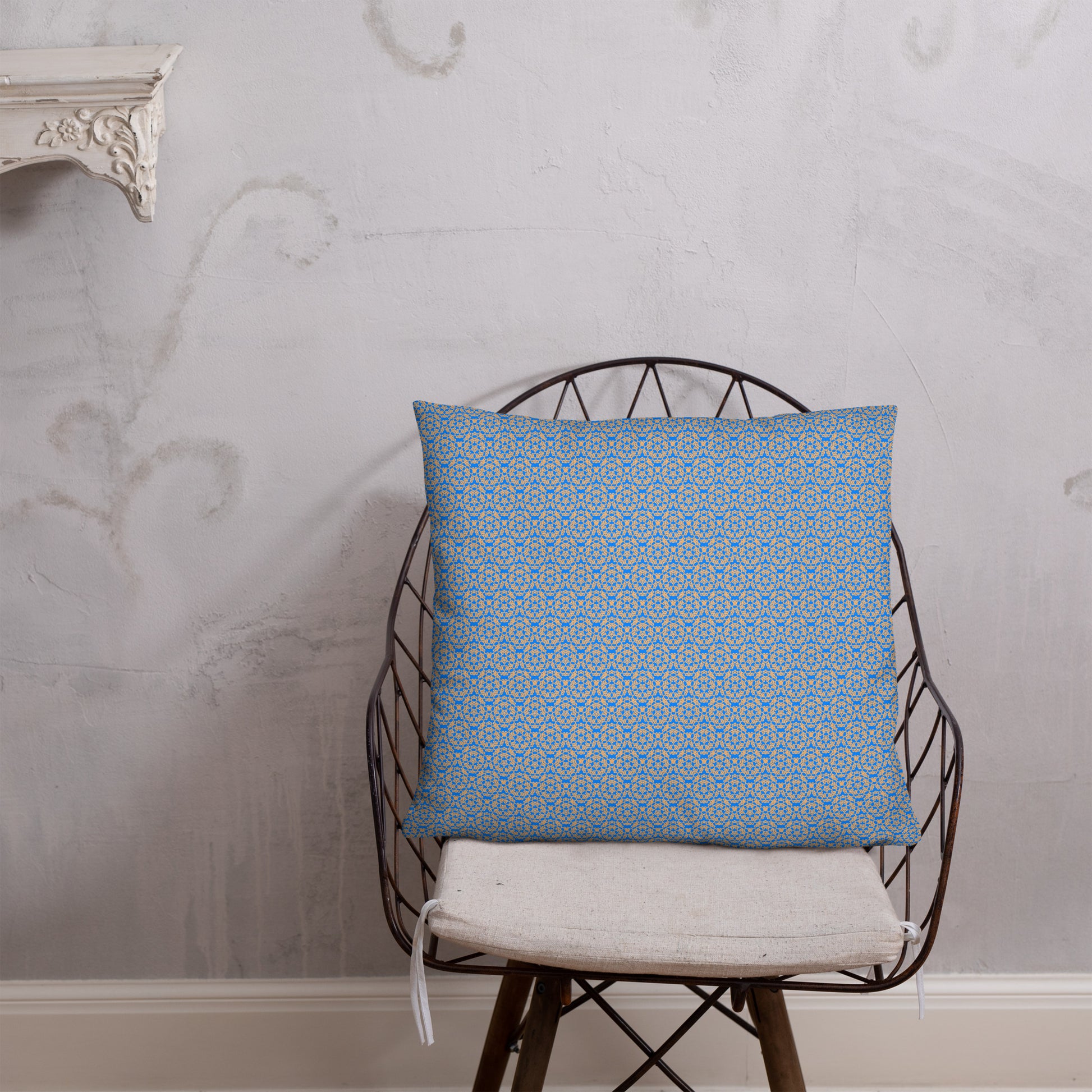 Front of the 22″×22″ basic pillow with the 'Pentagon' blue and yellow fractal geometric pattern on a chair.
