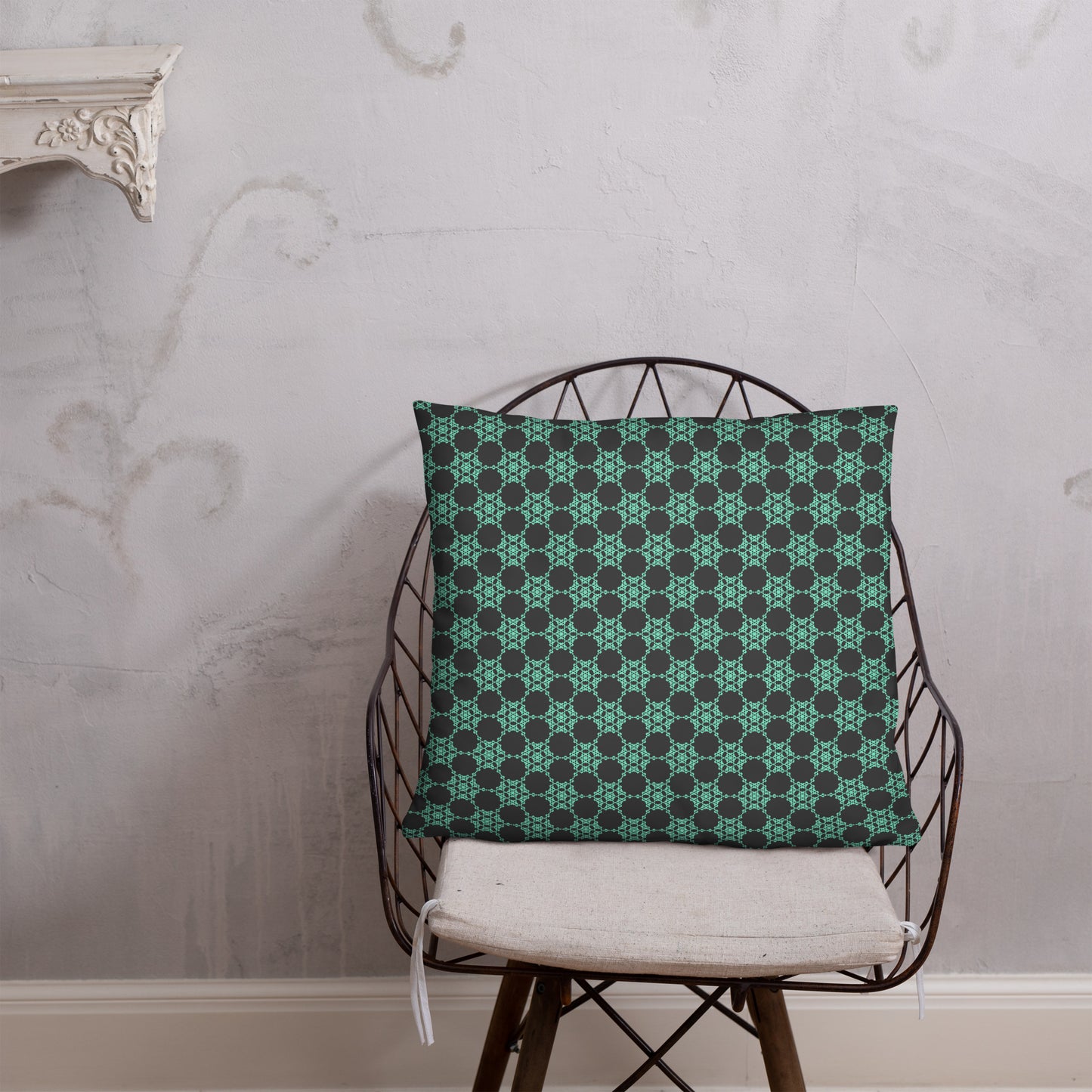 22″×22″ throw pillow with the 'Flowers Victory' charcoal and mint geometric pattern on a chair.