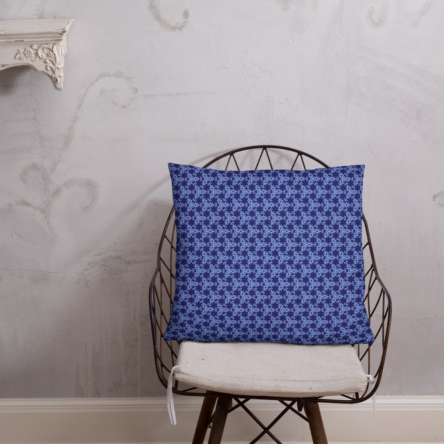 22″×22″ throw pillow with the 'Triagon' navy and blue geometric pattern on a chair.