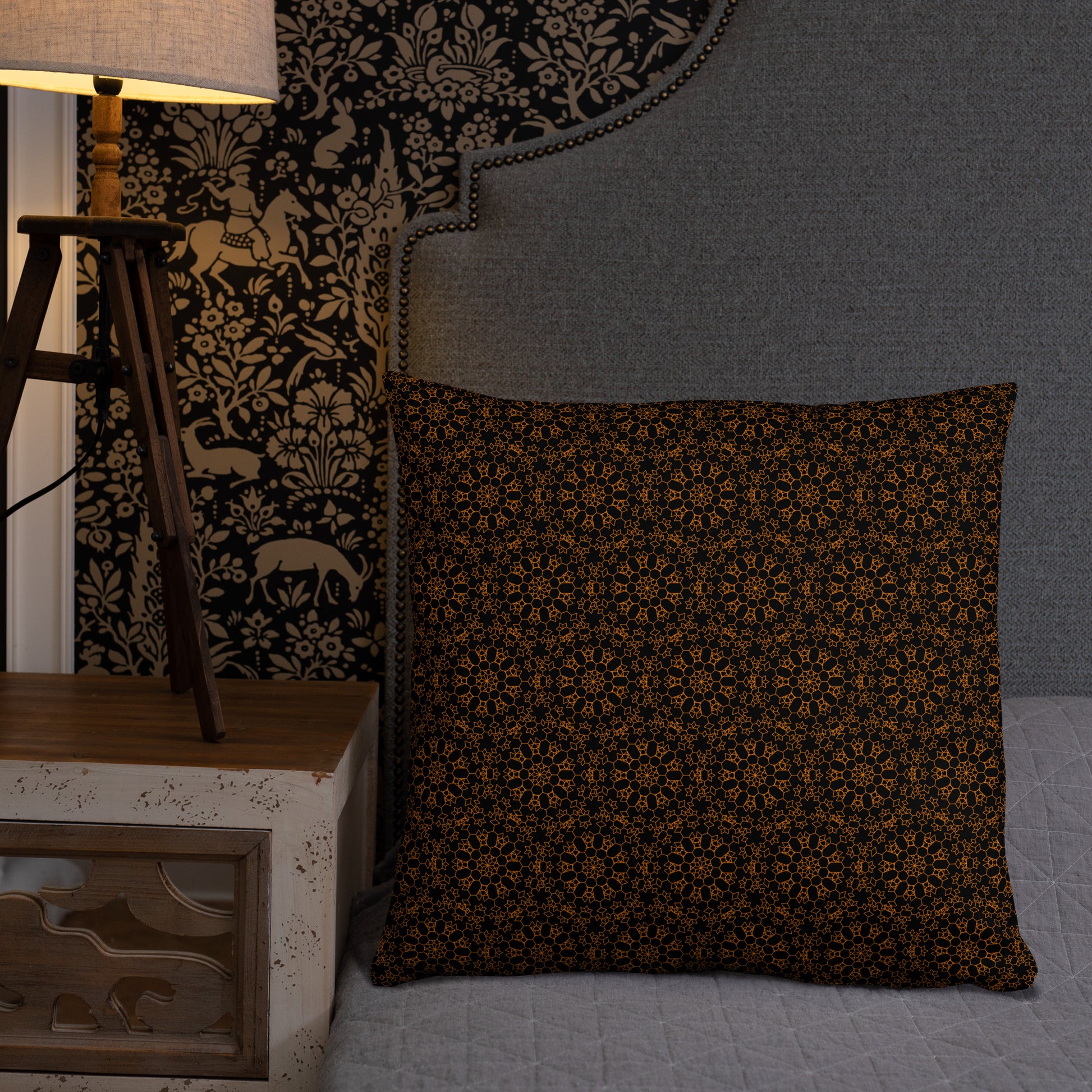 22″×22″ throw pillow with the 'Enneagon' black & gold geometric pattern on a bed with upholstered headboard.
