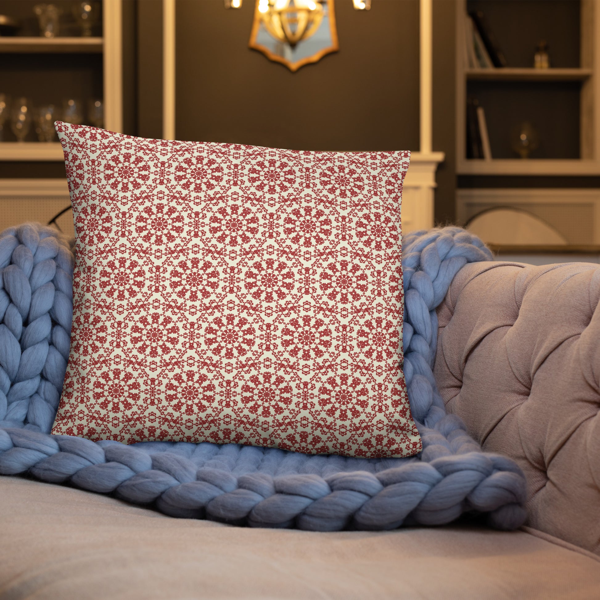 22″×22″ throw pillow with the ‘Decagon’ terracotta and beige geometric pattern on a blue sofa with a chunky knit blanket.