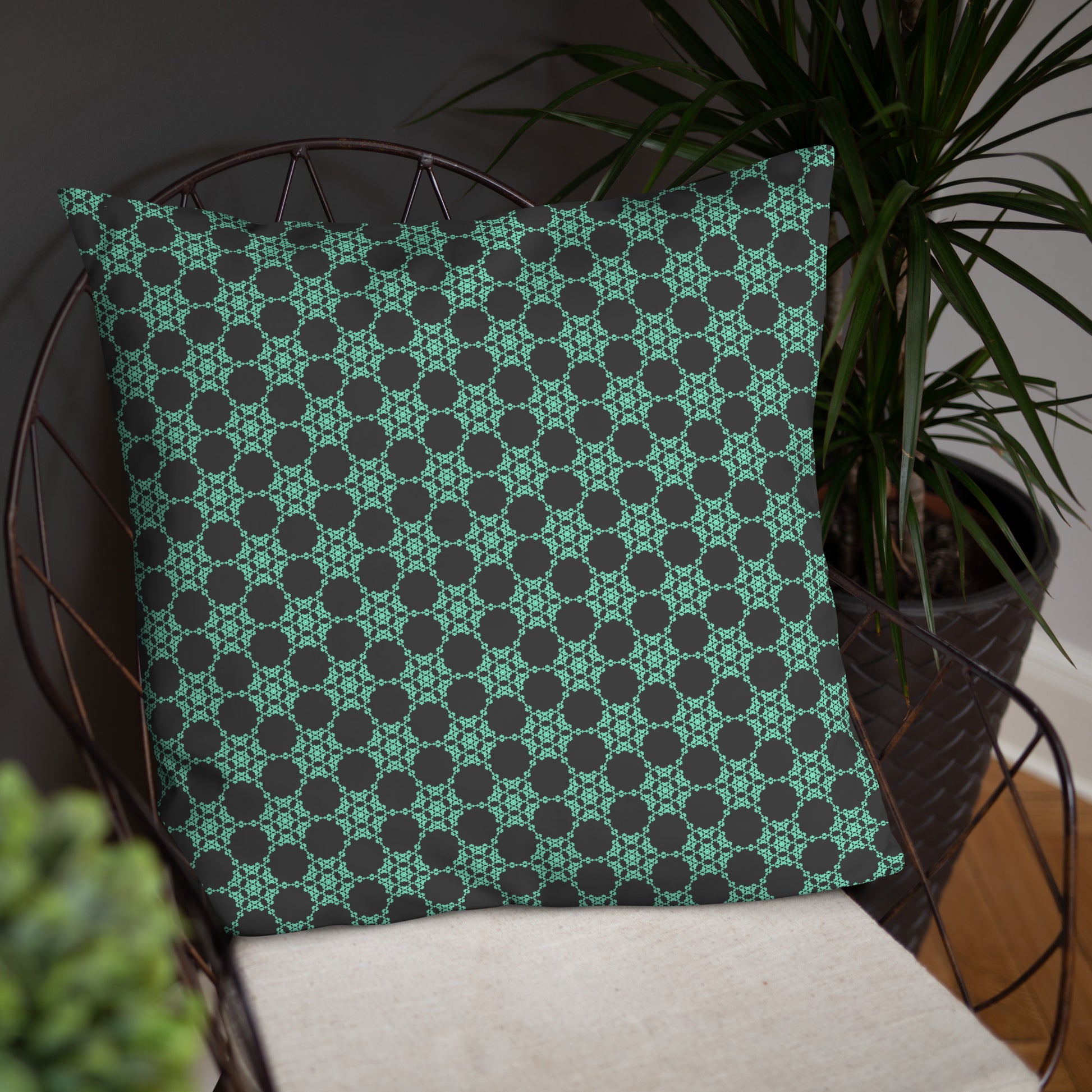 22″×22″ throw pillow with the 'Flowers Victory' charcoal and mint geometric pattern on a chair.