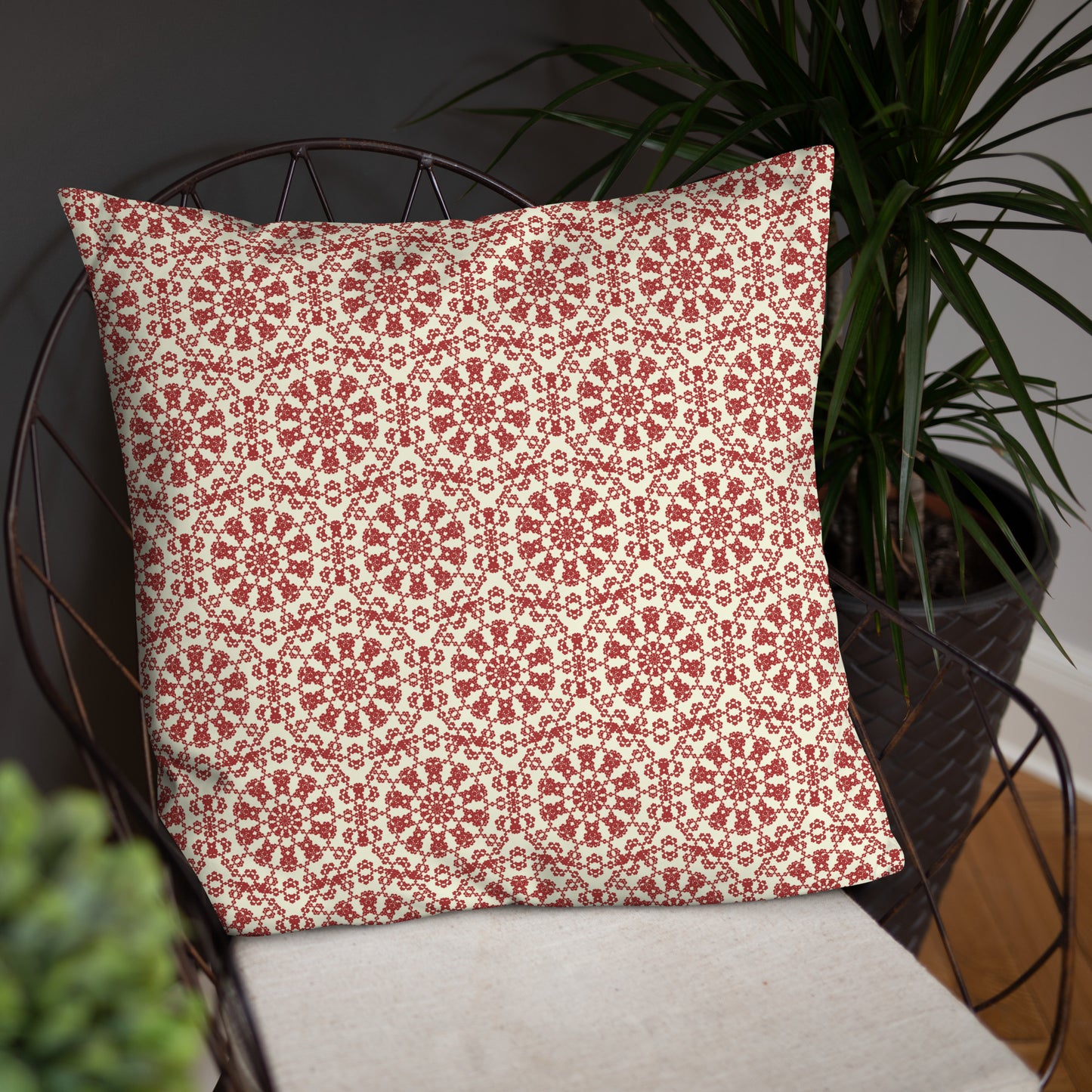 22″×22″ throw pillow with the ‘Decagon’ terracotta and beige geometric pattern on a wire chair against a dark background.