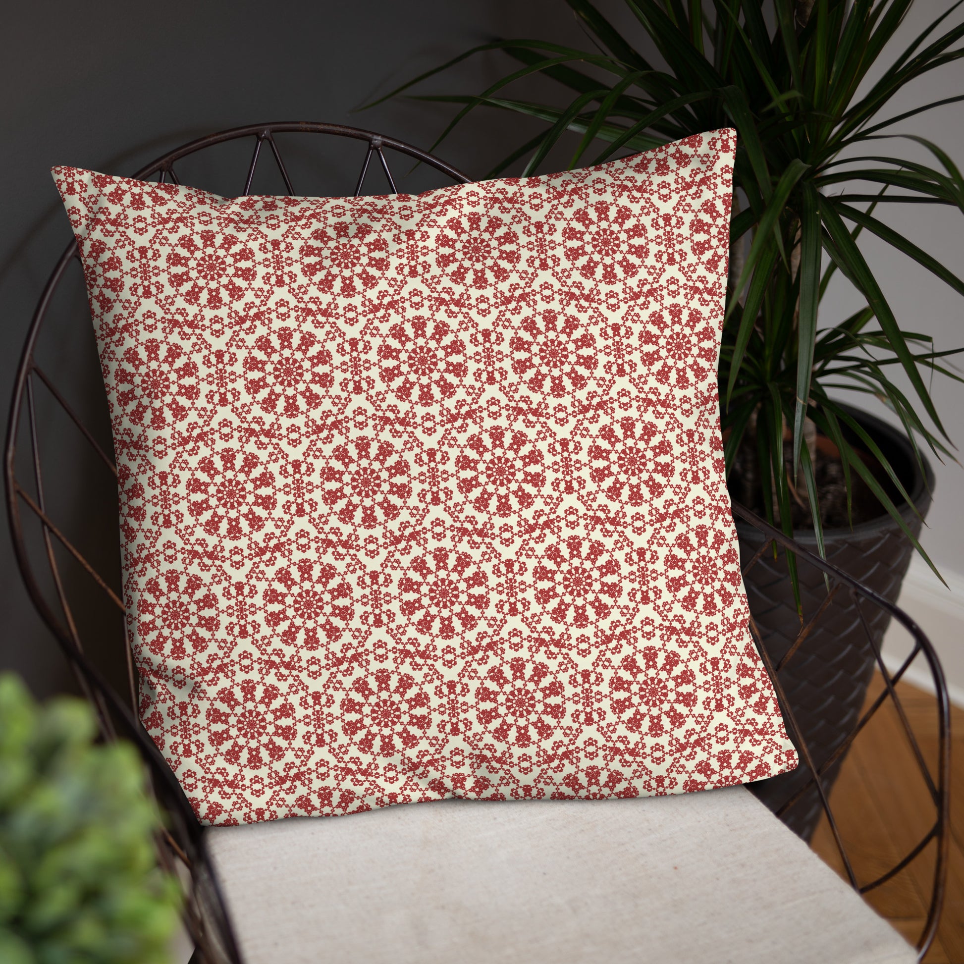 22″×22″ throw pillow with the ‘Decagon’ terracotta and beige geometric pattern on a wire chair against a dark background.