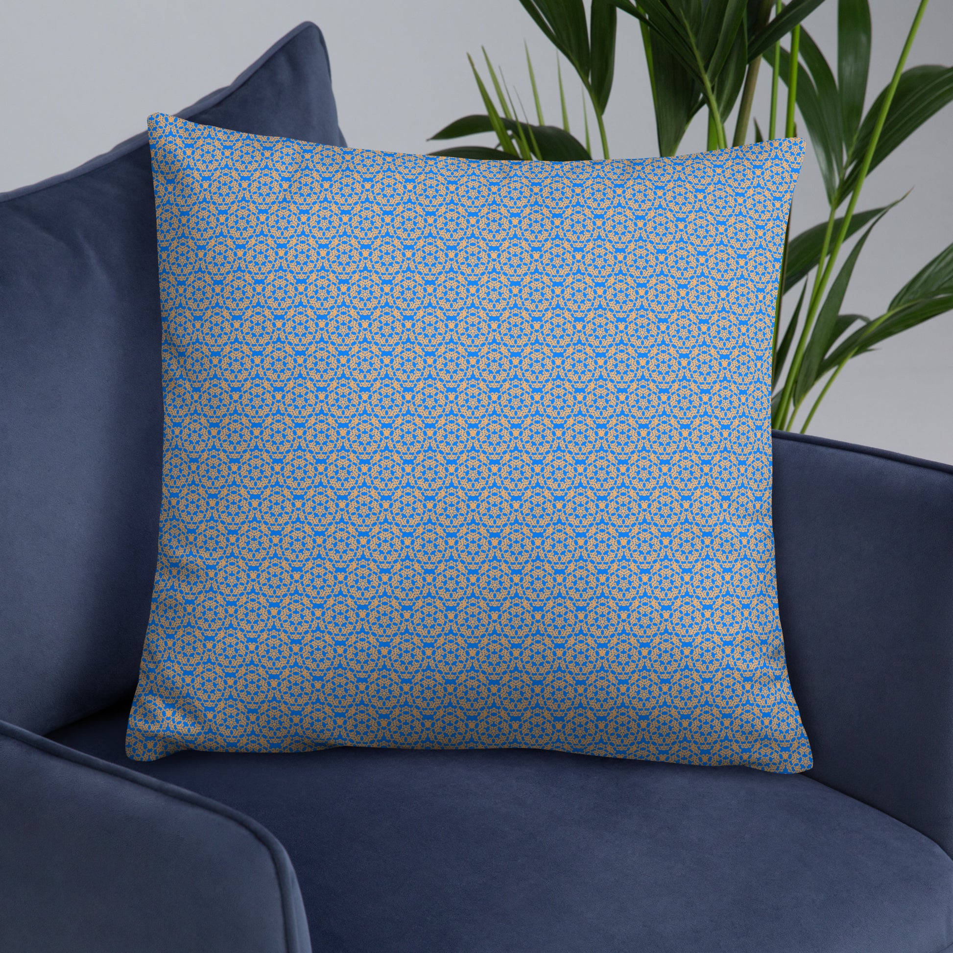 Front of the 22″×22″ basic pillow with the 'Pentagon' blue and yellow fractal geometric pattern on an armchair.