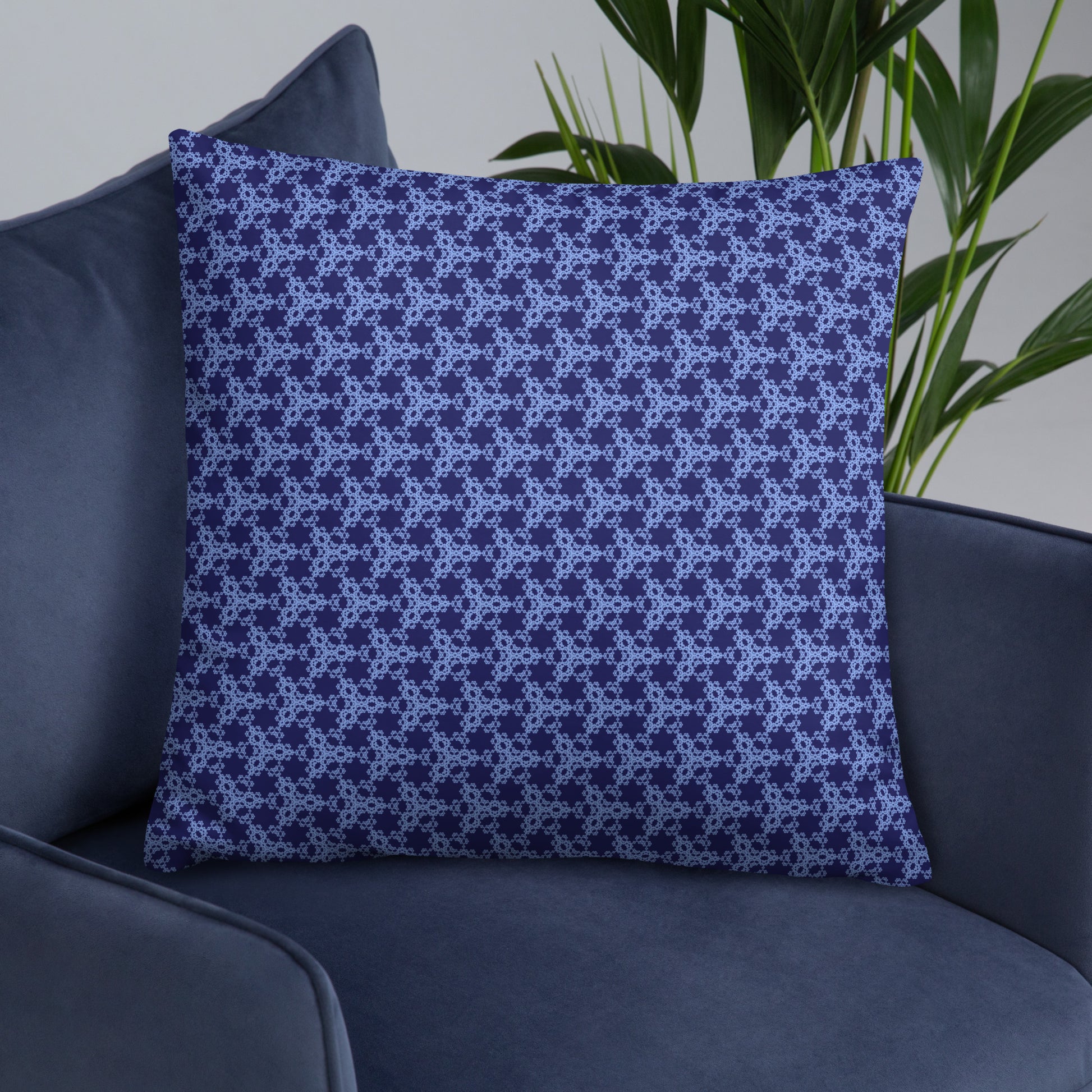 22″×22″ throw pillow with the 'Triagon' navy and blue geometric pattern on an armchair.
