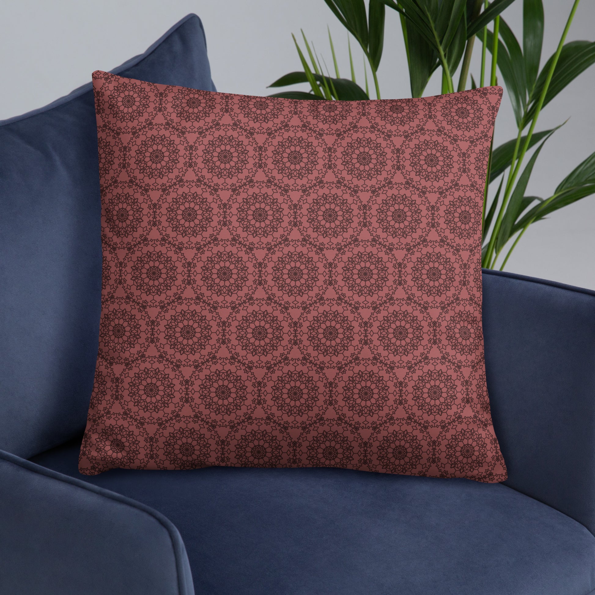 22″×22″ throw pillow with the 'Dodecagon' rose geometric pattern on navy blue armchair.