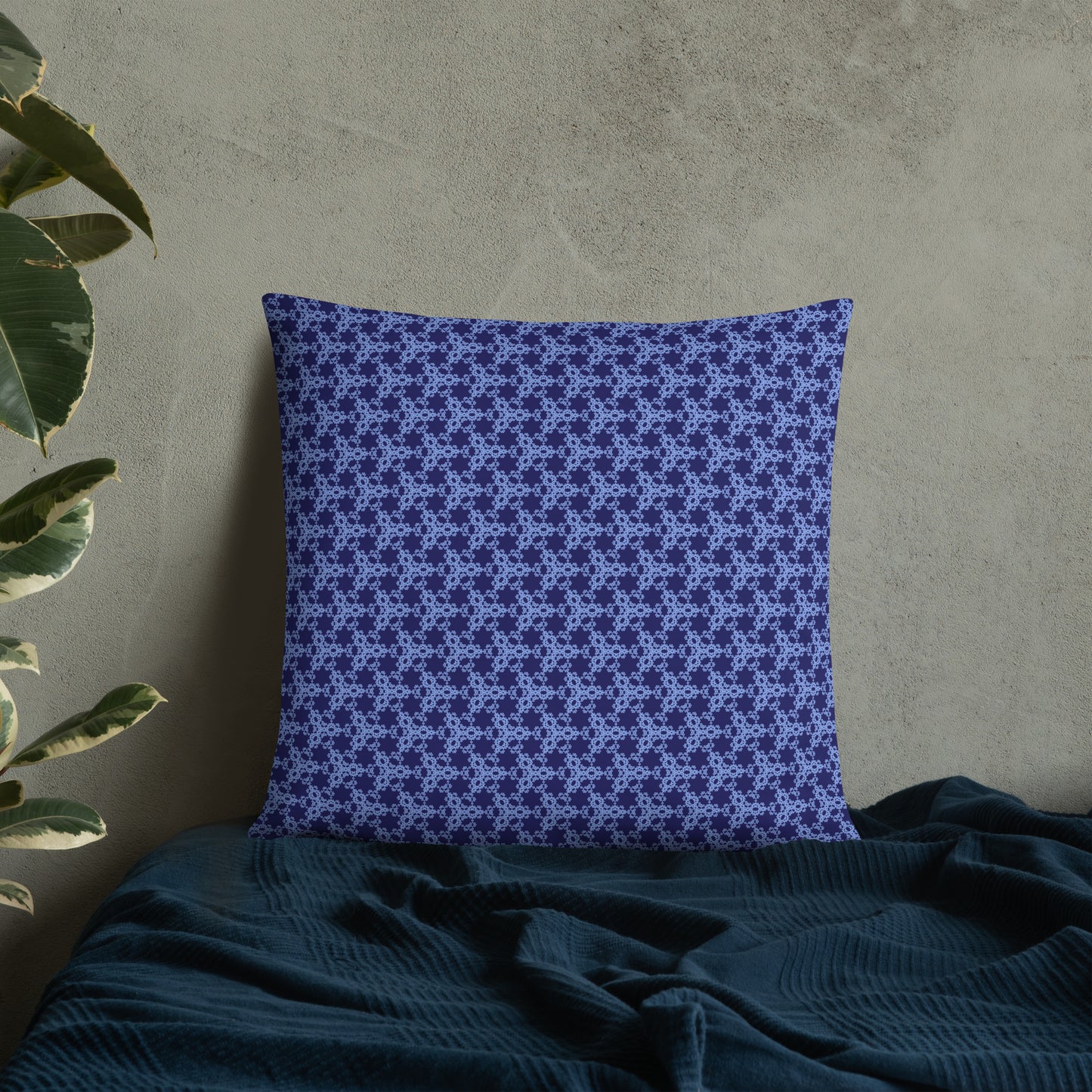 22″×22″ throw pillow with the 'Trigon' navy and blue geometric pattern on a bed.