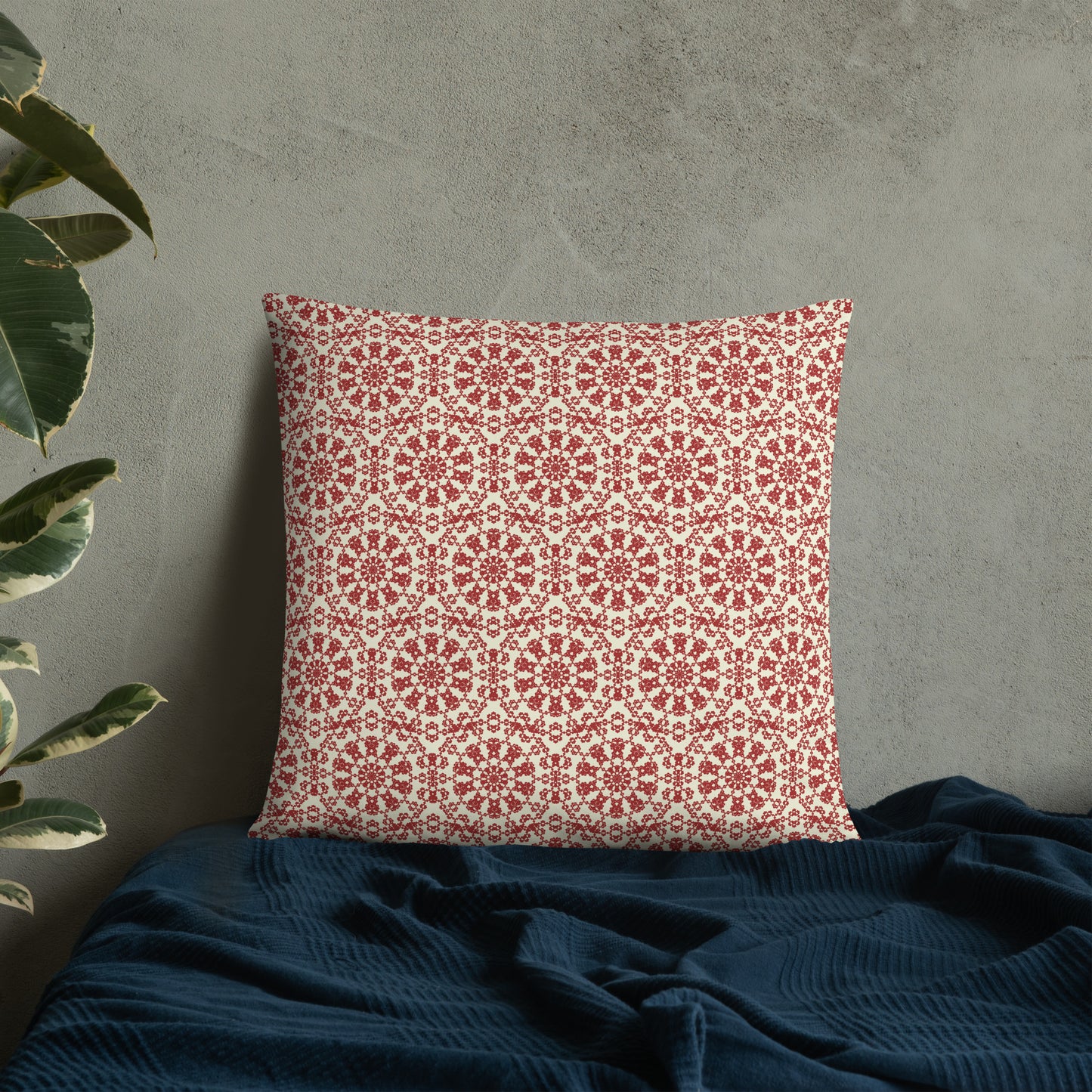 22″×22″ throw pillow with the ‘Decagon’ terracotta and beige geometric pattern on a bed with a dark navy blanket.