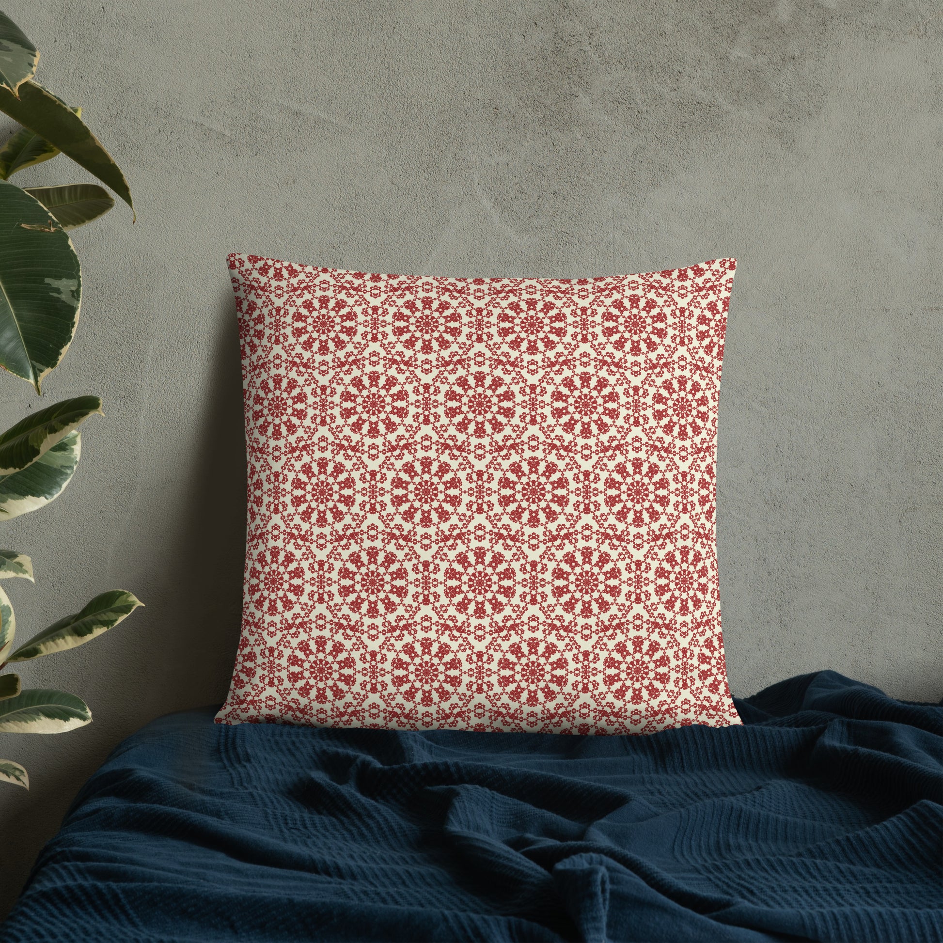 22″×22″ throw pillow with the ‘Decagon’ terracotta and beige geometric pattern on a bed with a dark navy blanket.