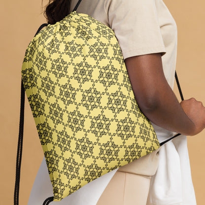 Close up of the drawstring bag with the 'Hexagon' yellow and black fractal geometric pattern slung over a woman's shoulder.