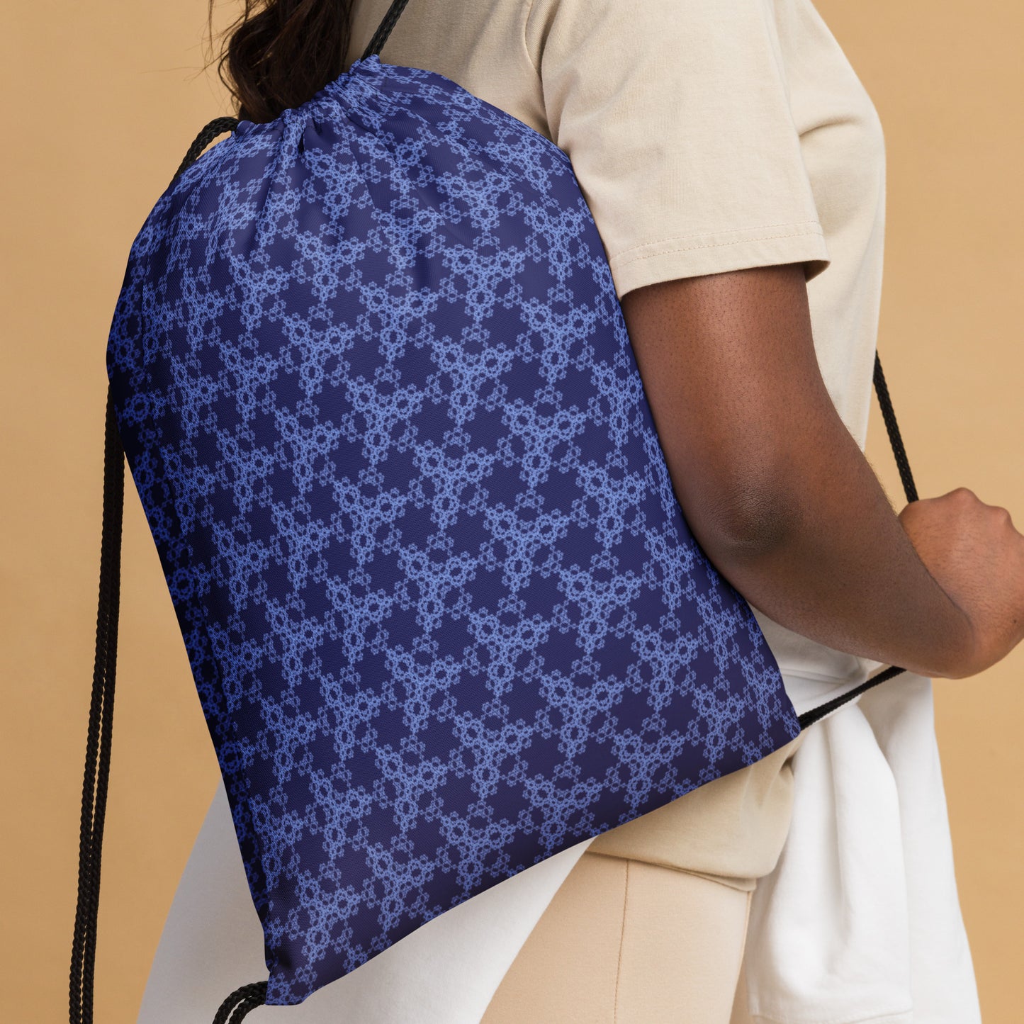 Close up of the drawstring bag with the 'Triagon' navy and blue fractal geometric pattern slung over a woman's shoulder.