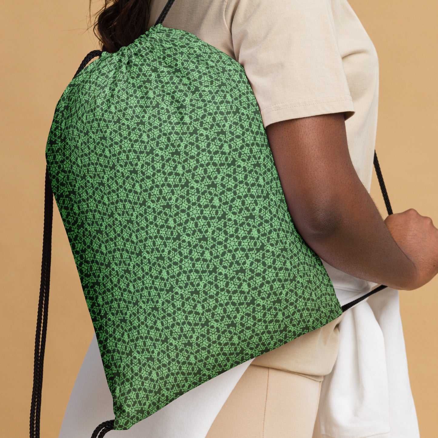 Close up of the drawstring bag with the 'Heptagon' green fractal geometric pattern slung over a woman's shoulder.