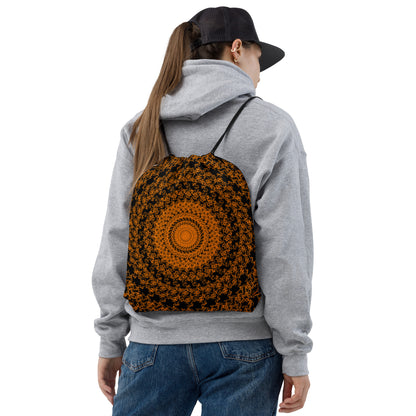 Back shot of a young woman wearing the drawstring bag with the 'The Sun' black and orange fractal design.