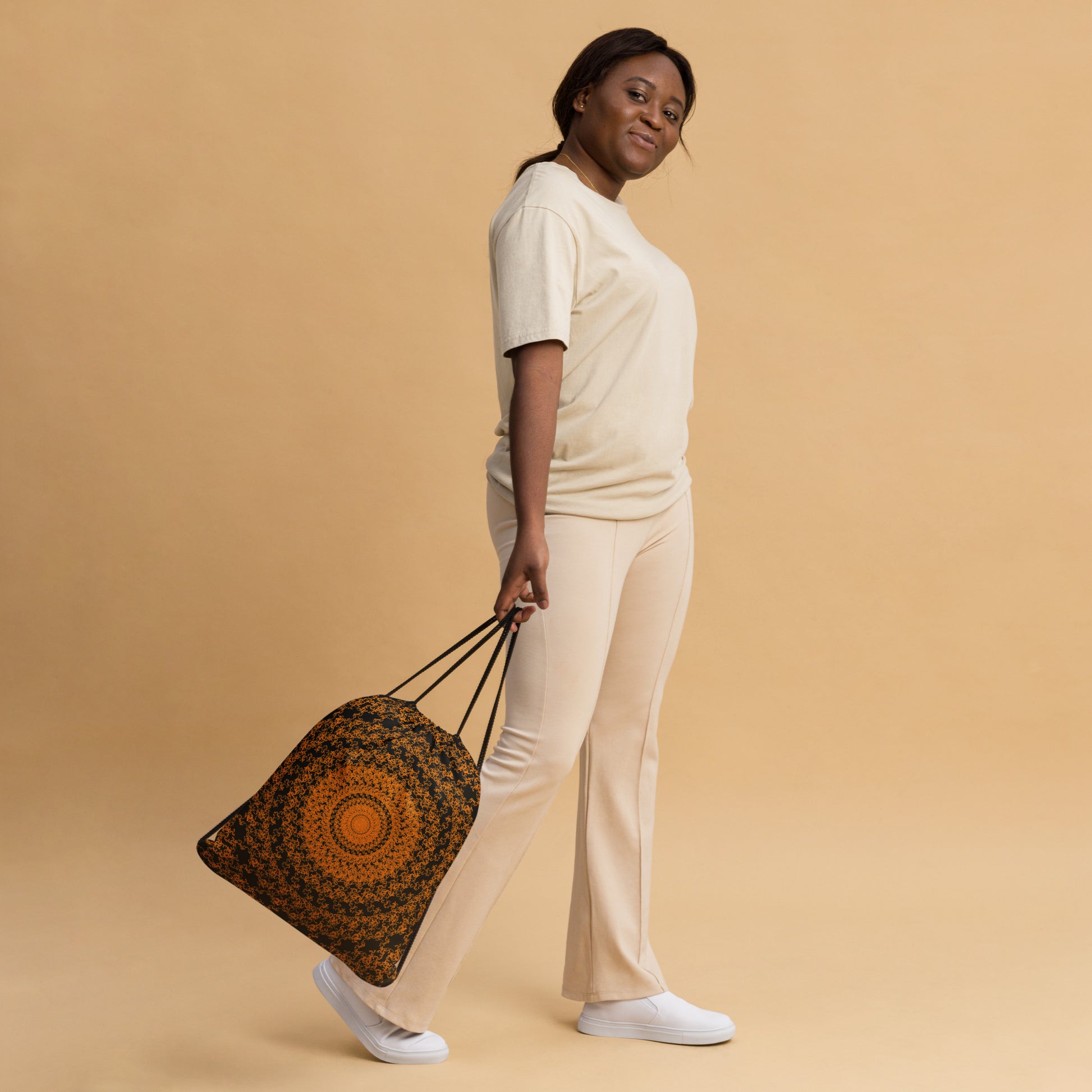 Woman slinging the drawstring bag with the 'The Sun' black and orange fractal design.