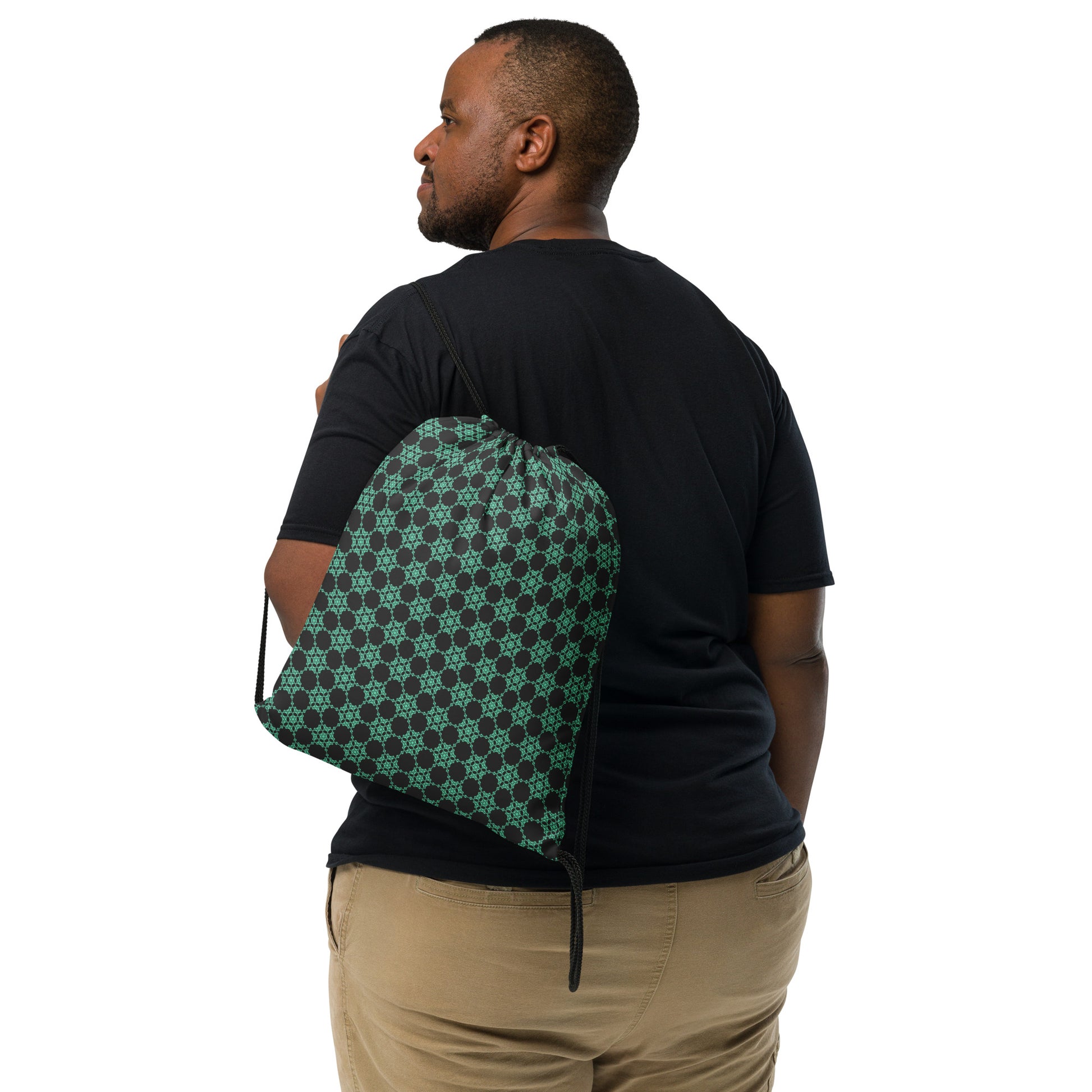 Back shot of the drawstring bag with the 'Flowers Victory' dark grey and green fractal geometric pattern slung over a man's shoulder.