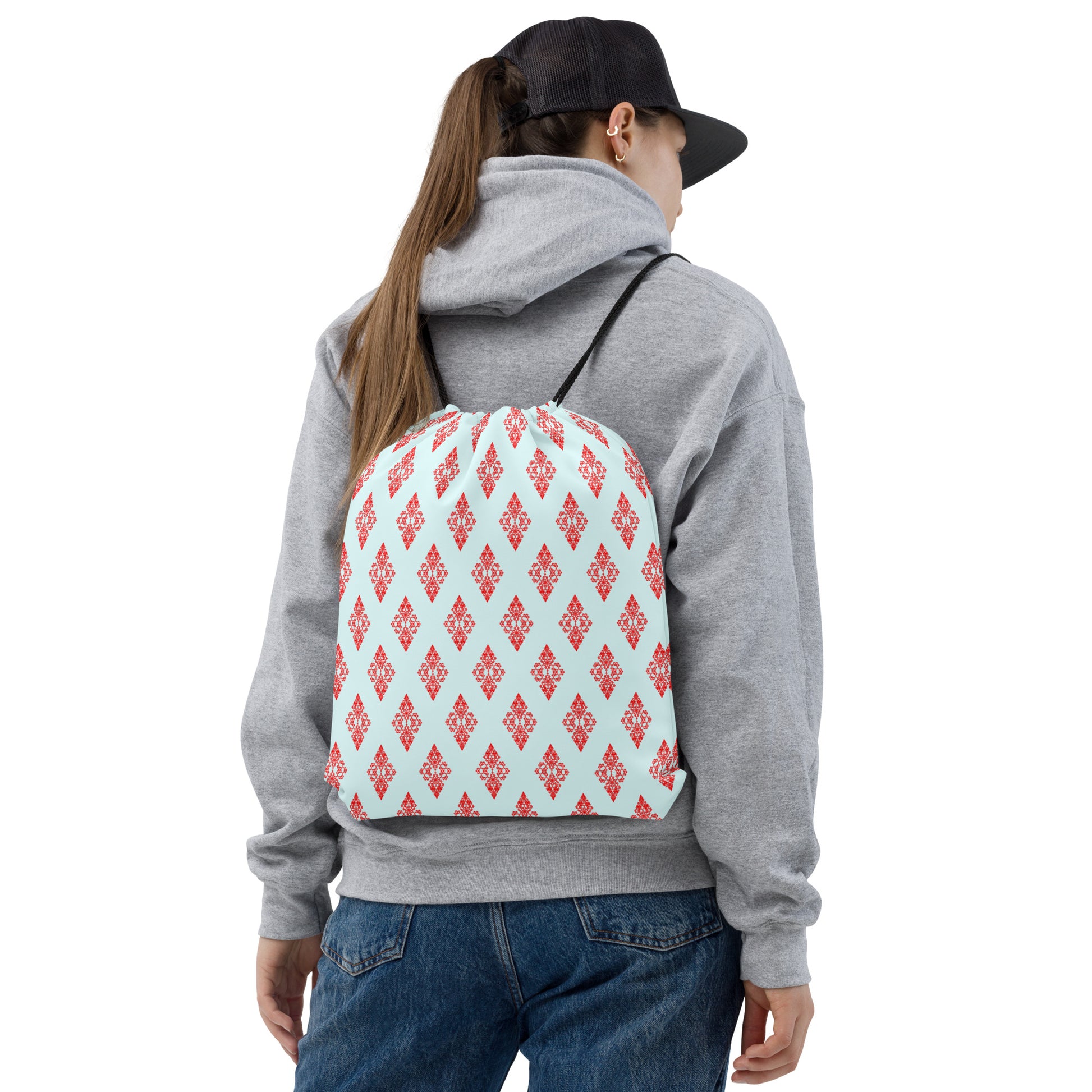 Back shot of a young woman wearing the drawstring bag with the 'Digon' sky blue and red fractal geometric pattern.
