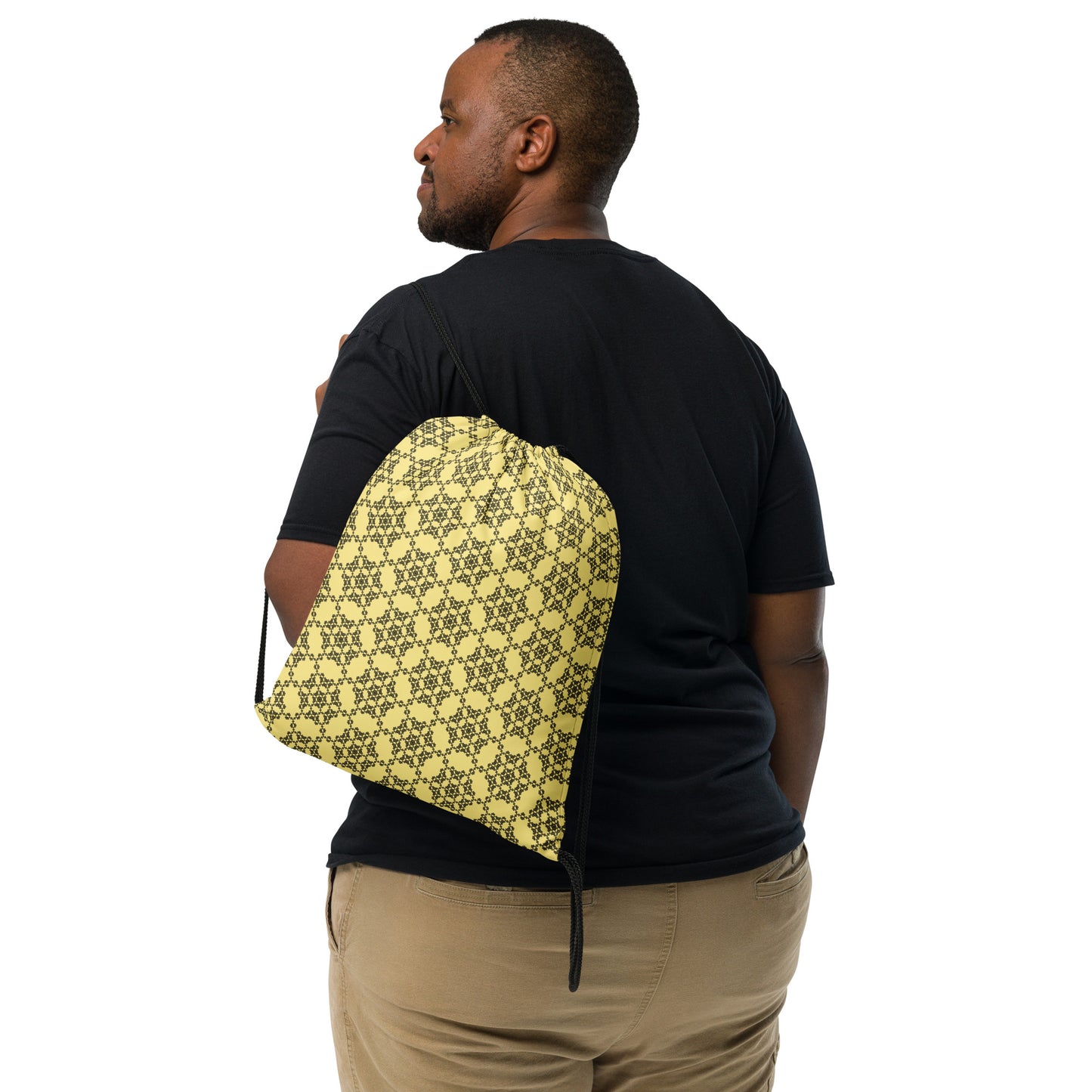 Back shot of the drawstring bag with the 'Hexagon' yellow and black fractal geometric pattern slung over a man's shoulder.