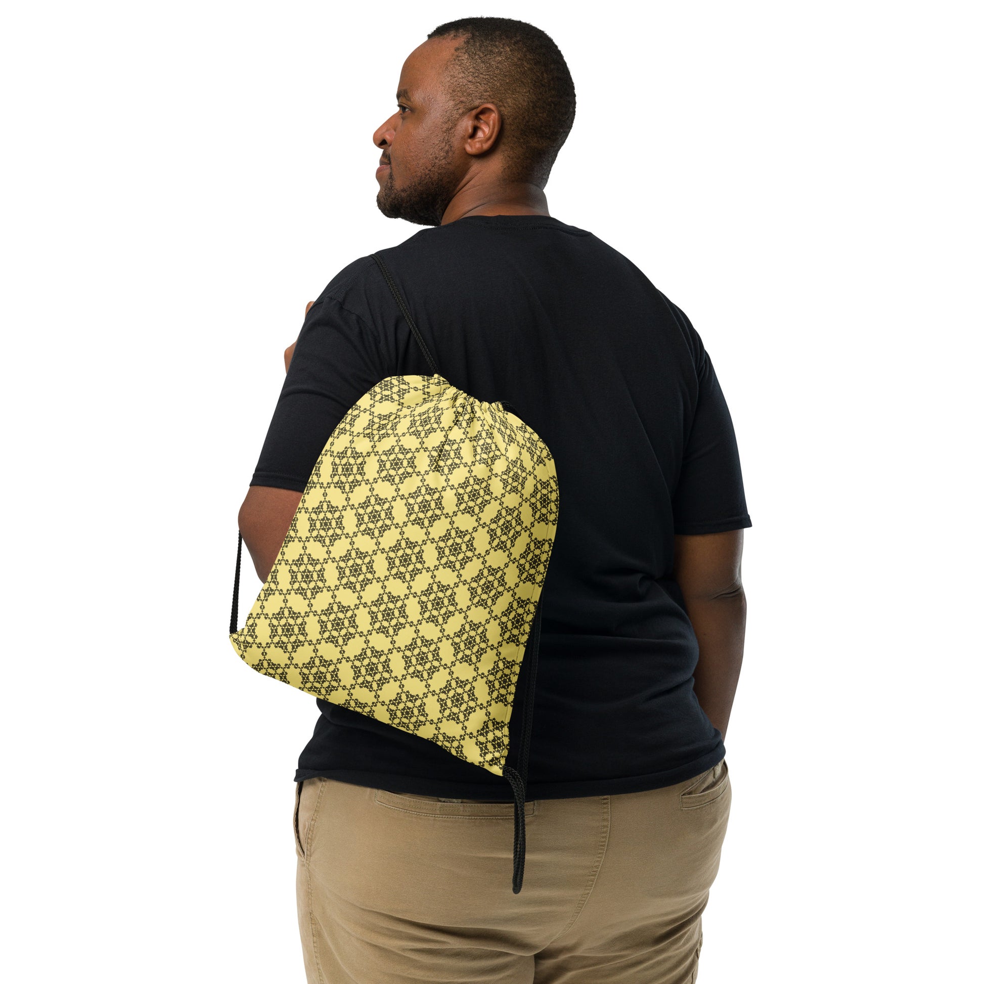 Back shot of the drawstring bag with the 'Hexagon' yellow and black fractal geometric pattern slung over a man's shoulder.