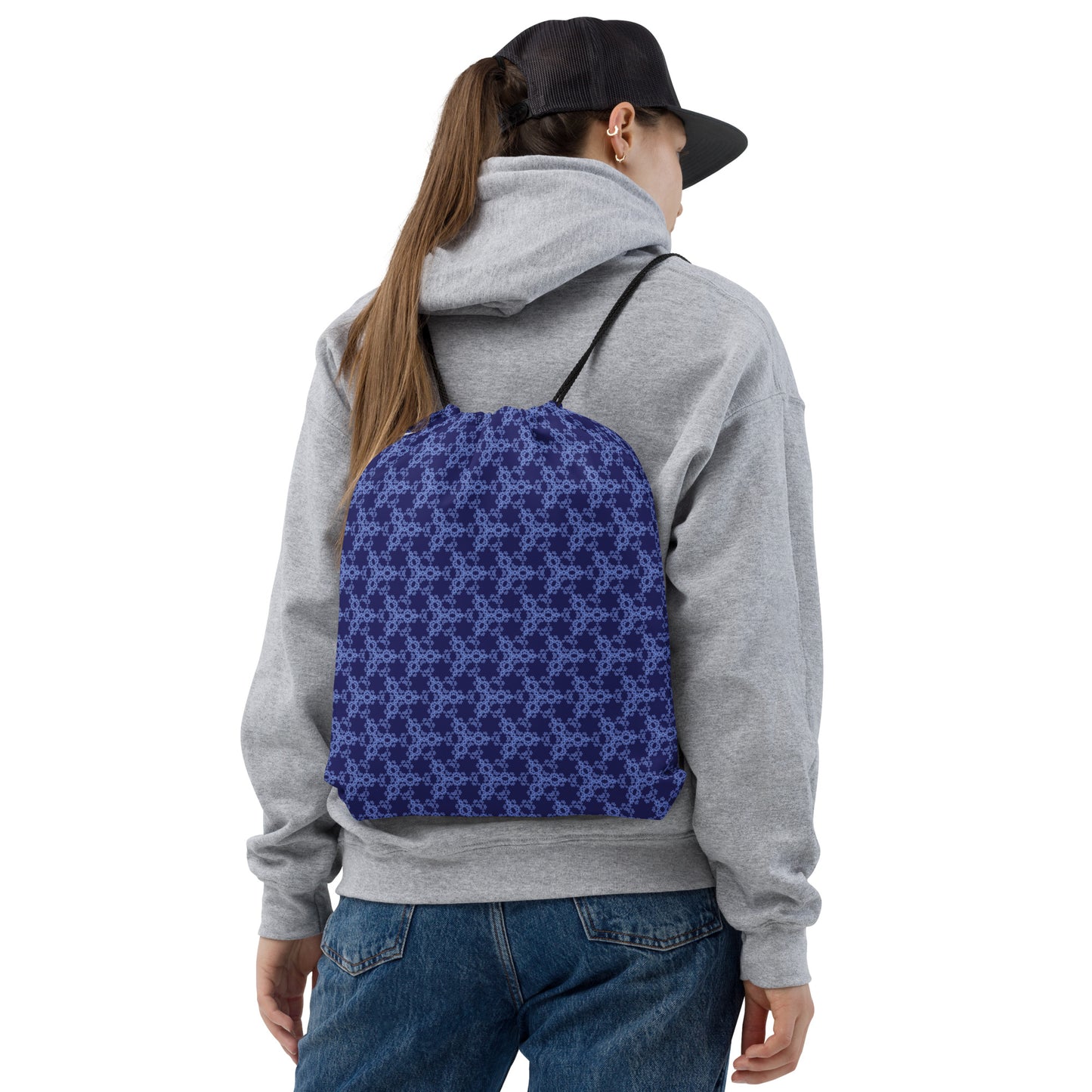 Back shot of a young woman wearing the drawstring bag with the 'Triagon' navy and blue fractal geometric pattern.
