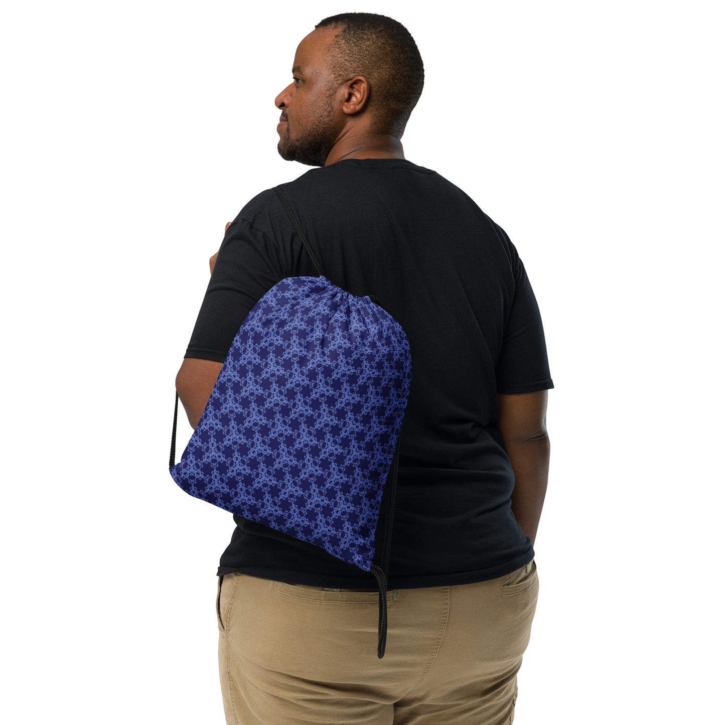 Back shot of the drawstring bag with the 'Triagon' navy and blue fractal geometric pattern slung over a man's shoulder.