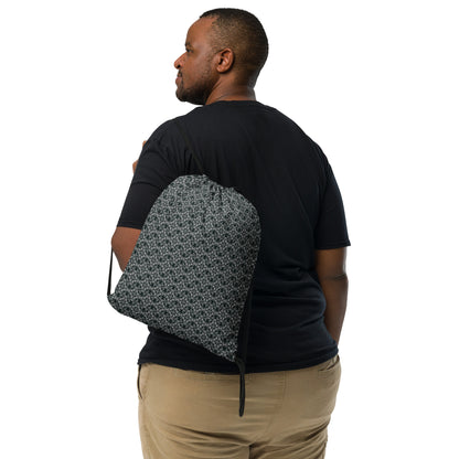 Back shot of the drawstring bag with the 'Quadragon' charcoal and white fractal geometric pattern slung over a man's shoulder.