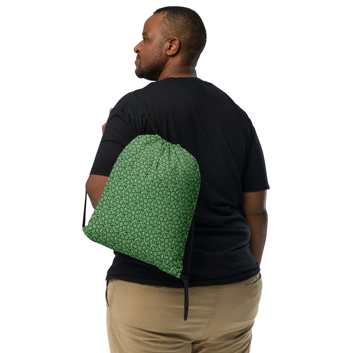 Back shot of the drawstring bag with the 'Heptagon' green fractal geometric pattern slung over a man's shoulder.