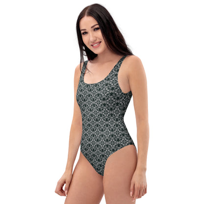 Left front shot of a model wearing the one-piece swimsuit with the 'Quadragon' charcoal and white fractal geometric pattern.