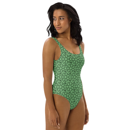 Right front shot of a model wearing the one-piece swimsuit with the 'Heptagon' green fractal geometric pattern.