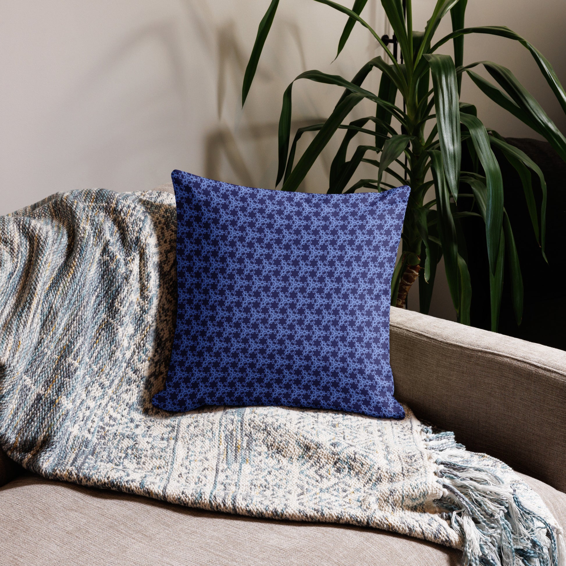 18″×18″ premium throw pillow with the 'Trigon' navy and blue geometric pattern on a couch.