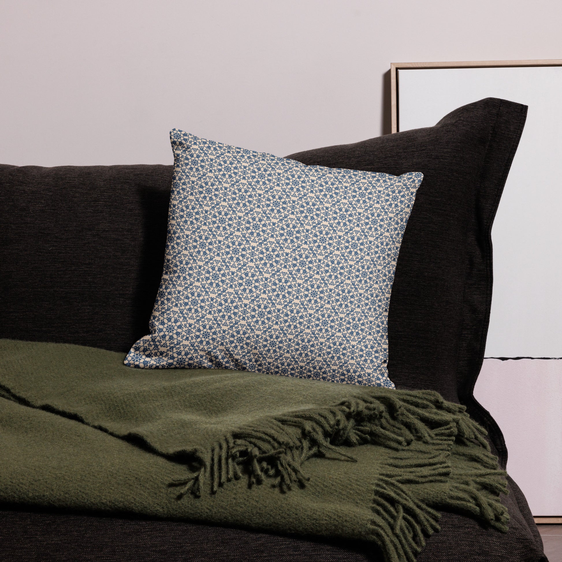 18″×18″ premium throw pillow with the ‘Octagon’ navy and beige geometric pattern on a dark sofa with throw blanket.