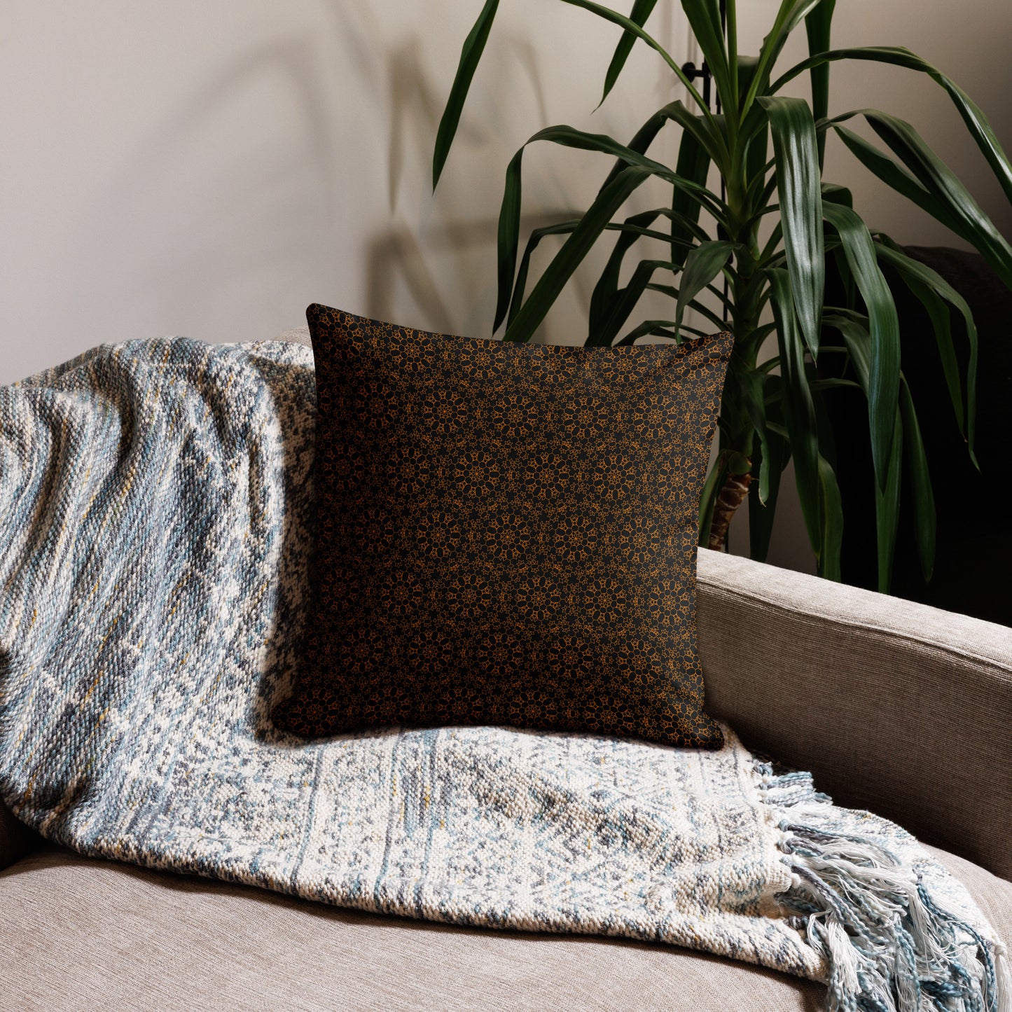 18″×18″ premium throw pillow with the 'Enneagon' black & gold geometric pattern on a sofa with textured throw blanket.