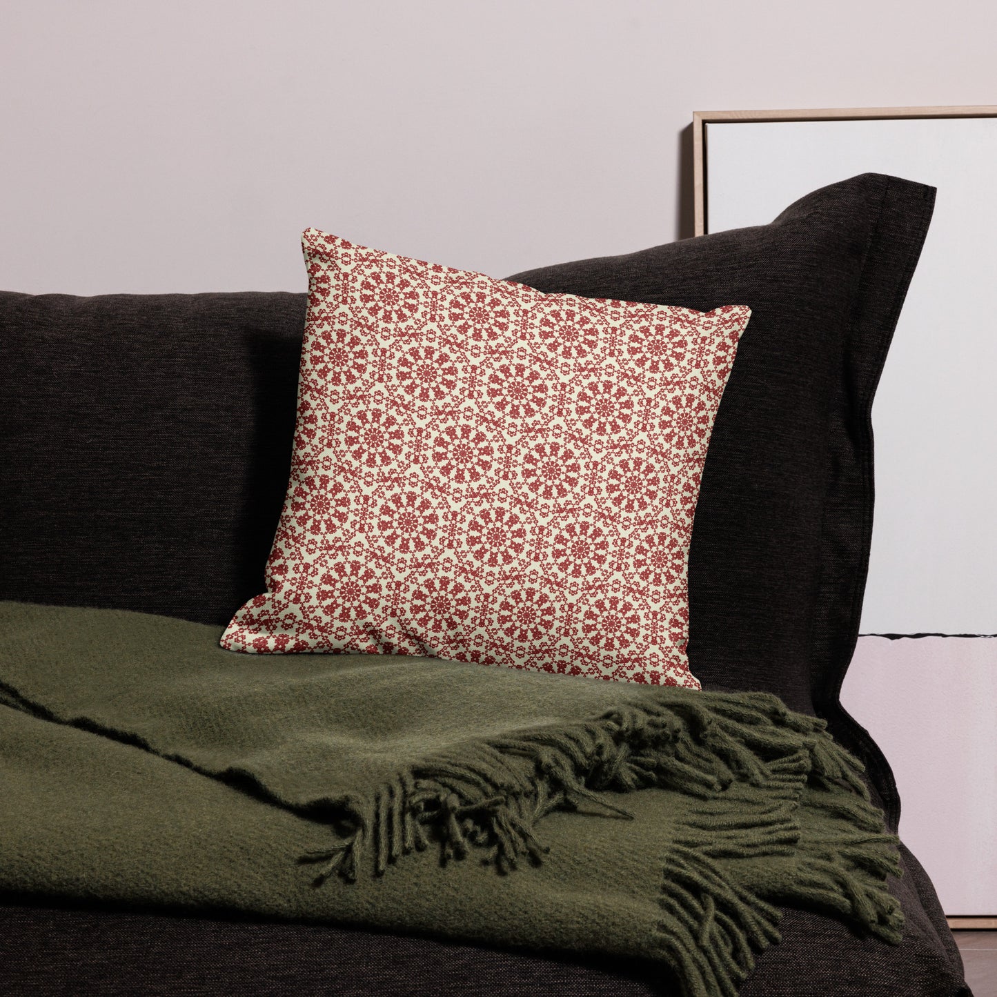 18″×18″ premium throw pillow with the ‘Decagon’ terracotta and beige geometric pattern on a black sofa with an olive throw.