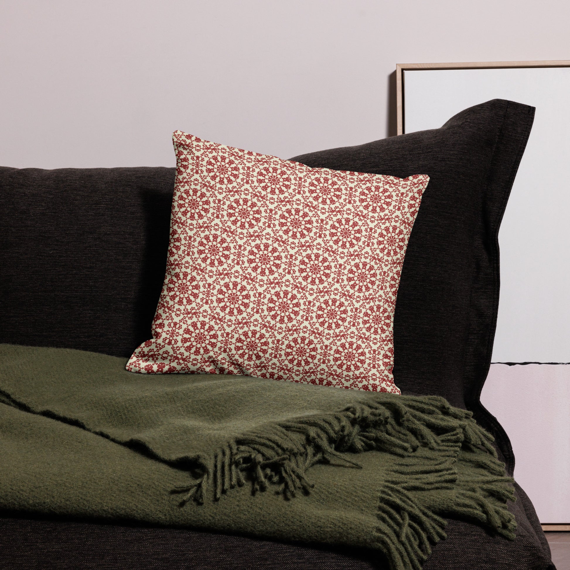 18″×18″ premium throw pillow with the ‘Decagon’ terracotta and beige geometric pattern on a black sofa with an olive throw.