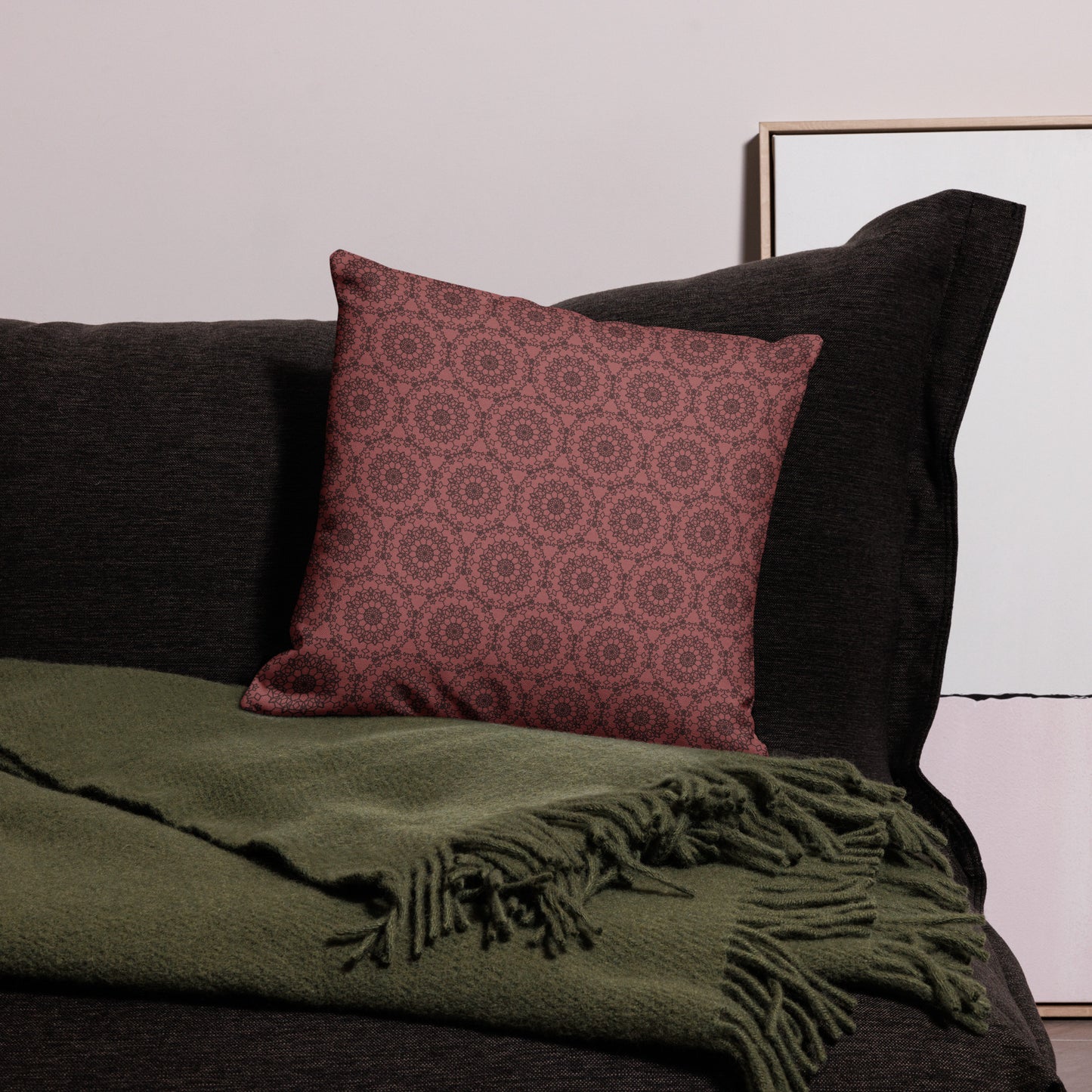 18″×18″ premium throw pillow with the 'Dodecagon' rose geometric pattern on dark sofa with green fringed throw.