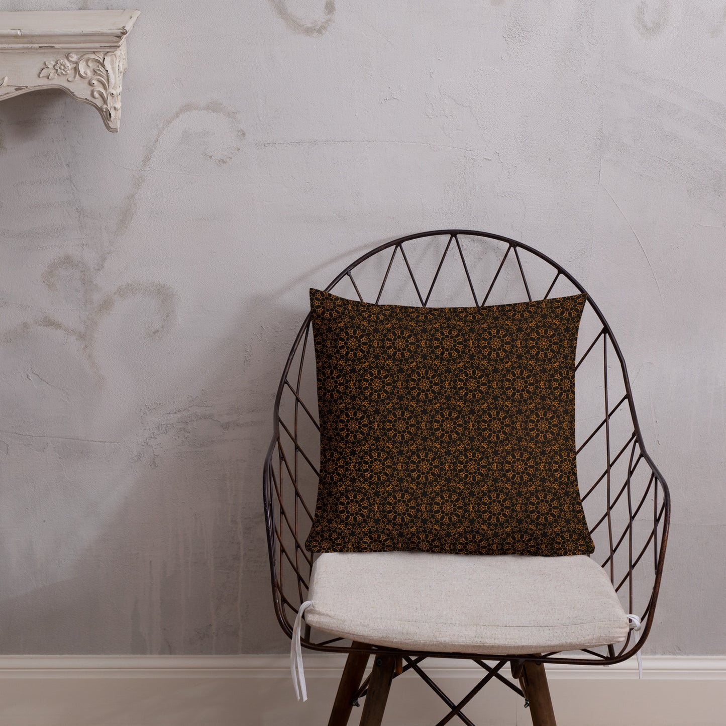 18″×18″ premium throw pillow with the 'Enneagon' black & gold geometric pattern on a wire chair.