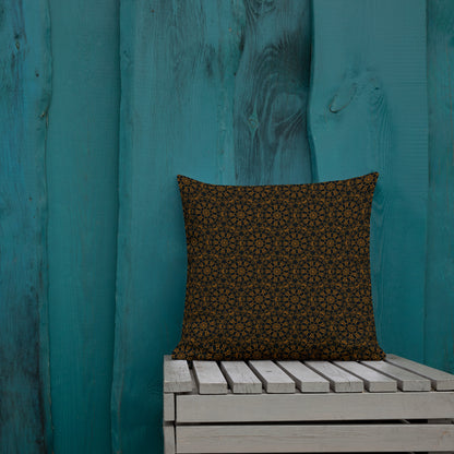 18″×18″ premium throw pillow with the 'Enneagon' black & gold geometric pattern on a wooden bench with teal wall.