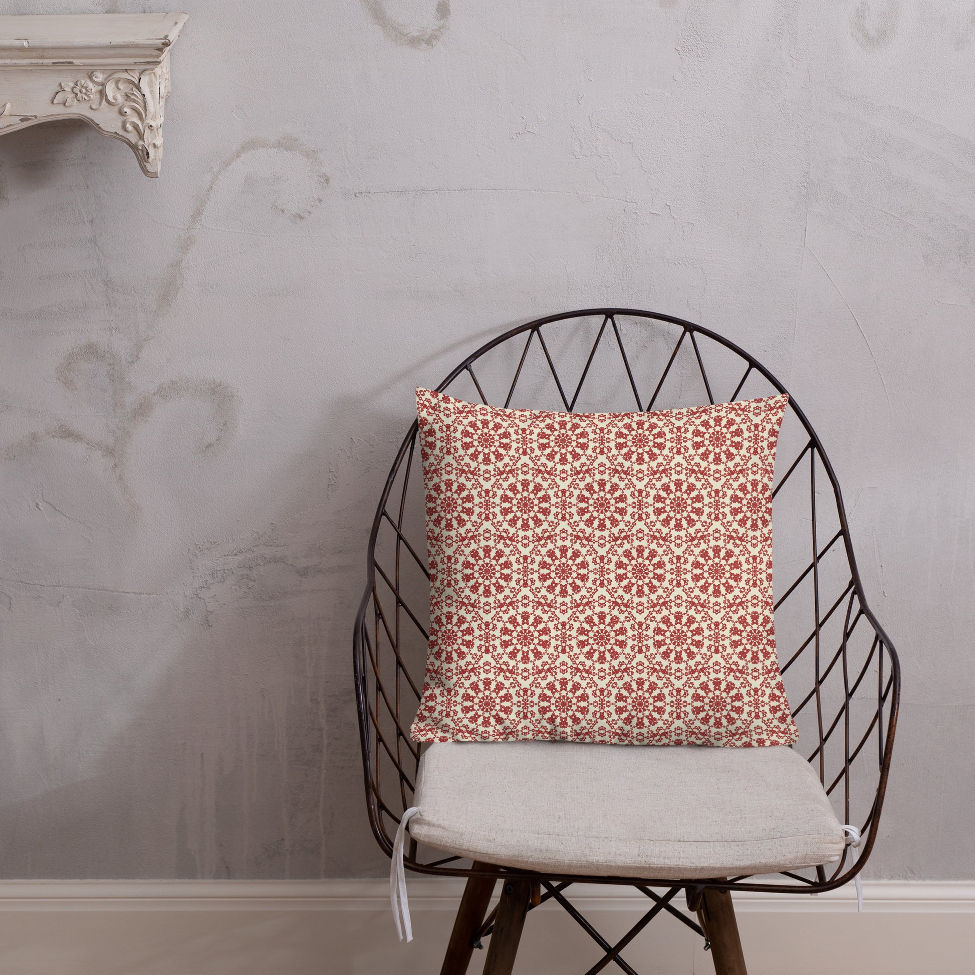 18″×18″ premium throw pillow with the ‘Decagon’ terracotta and beige geometric pattern on a wire chair against an ornate plaster wall.