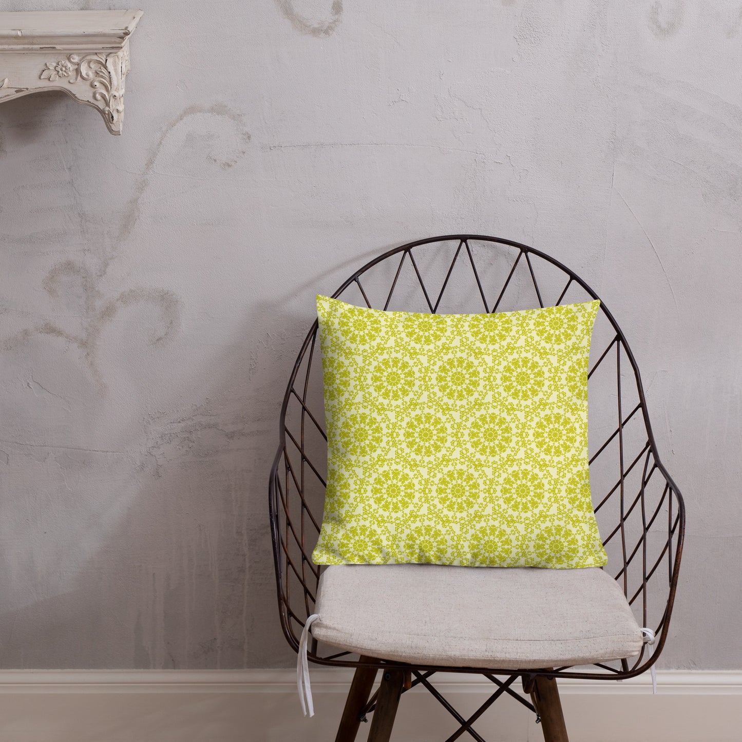 18″×18″ premium throw pillow with the 'Hendecagon' yellow-green geometric pattern on a wire chair with white plaster wall