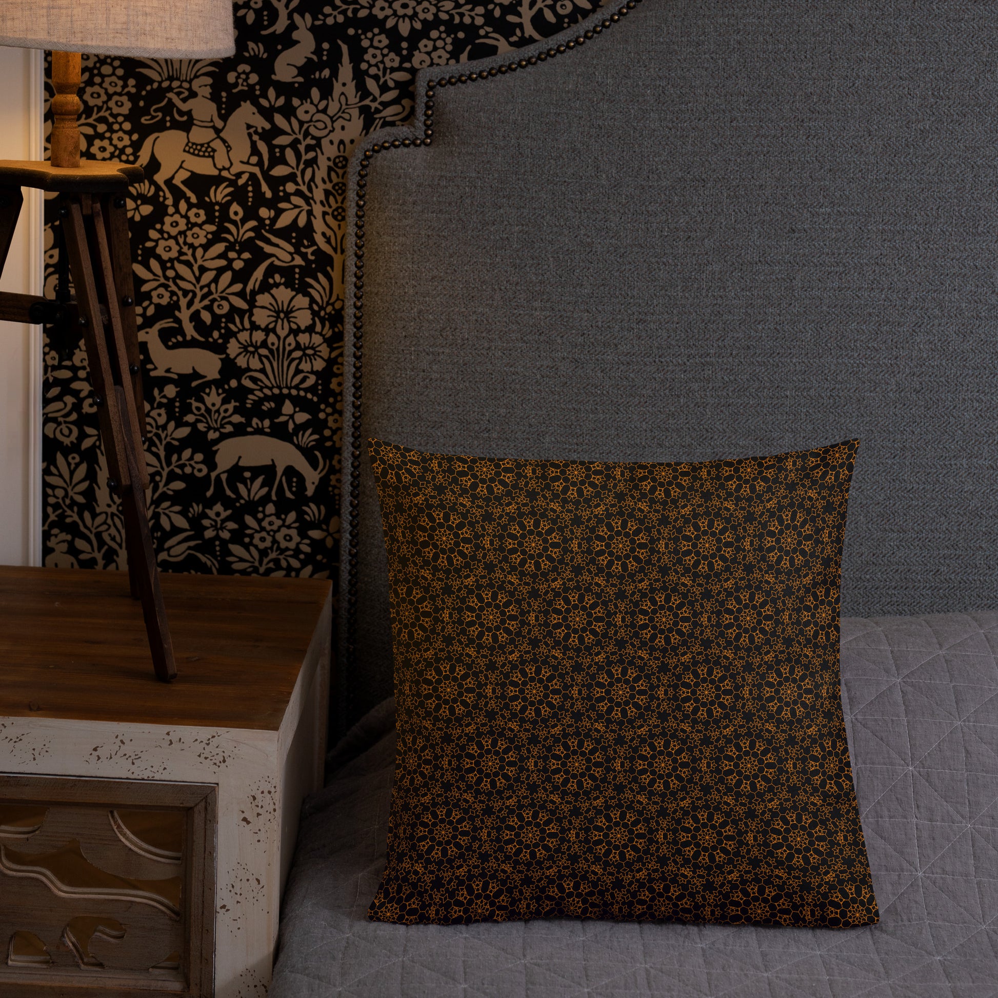 18″×18″ premium throw pillow with the 'Enneagon' black & gold geometric pattern on a bed with upholstered headboard.